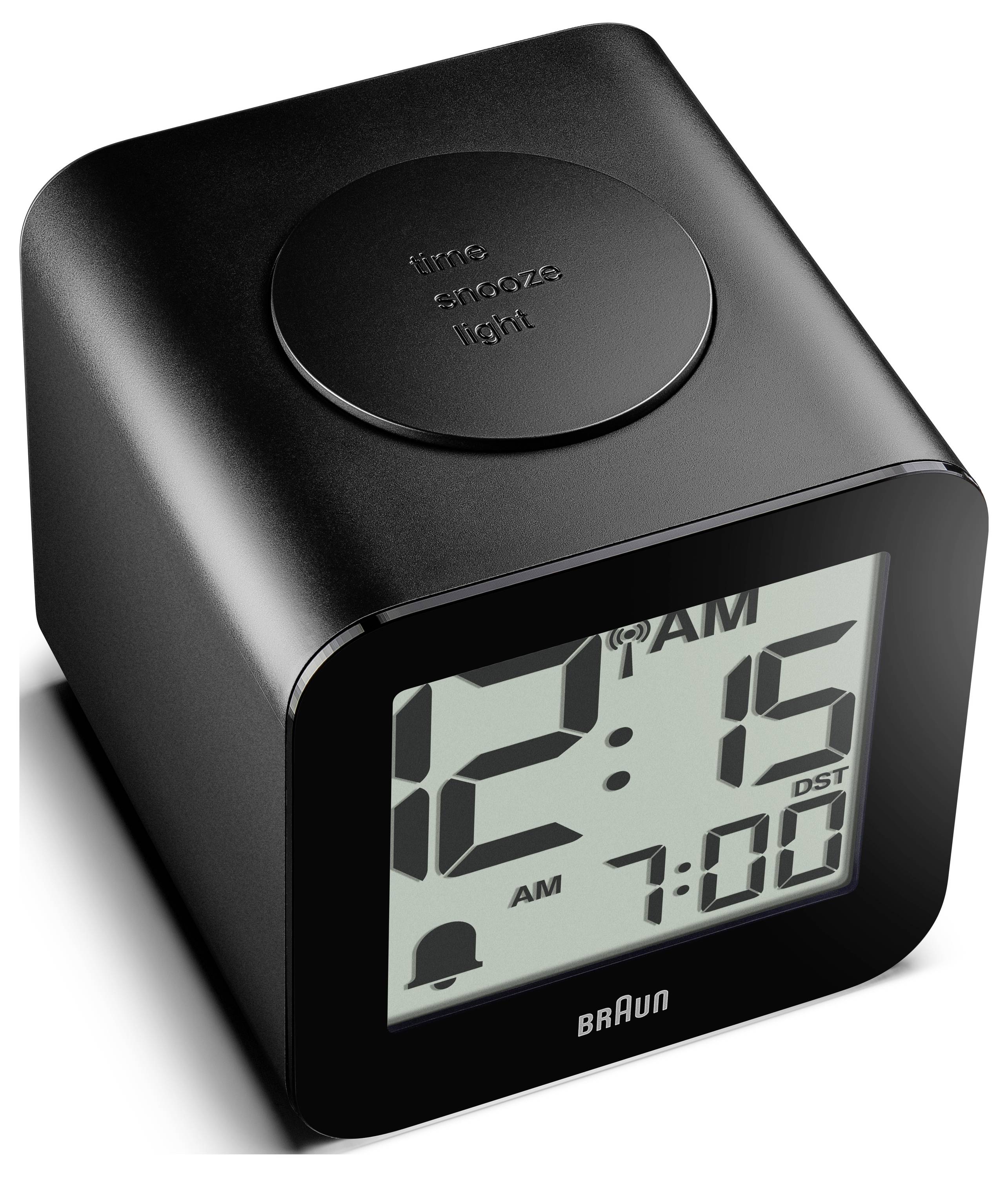 Digitální budík Black Braun zobrazující 12:15 AM s budíkem nastaveným na 7:00 a indikátorem letního času; kulatý horní tlačítko na přerušení alarmu.