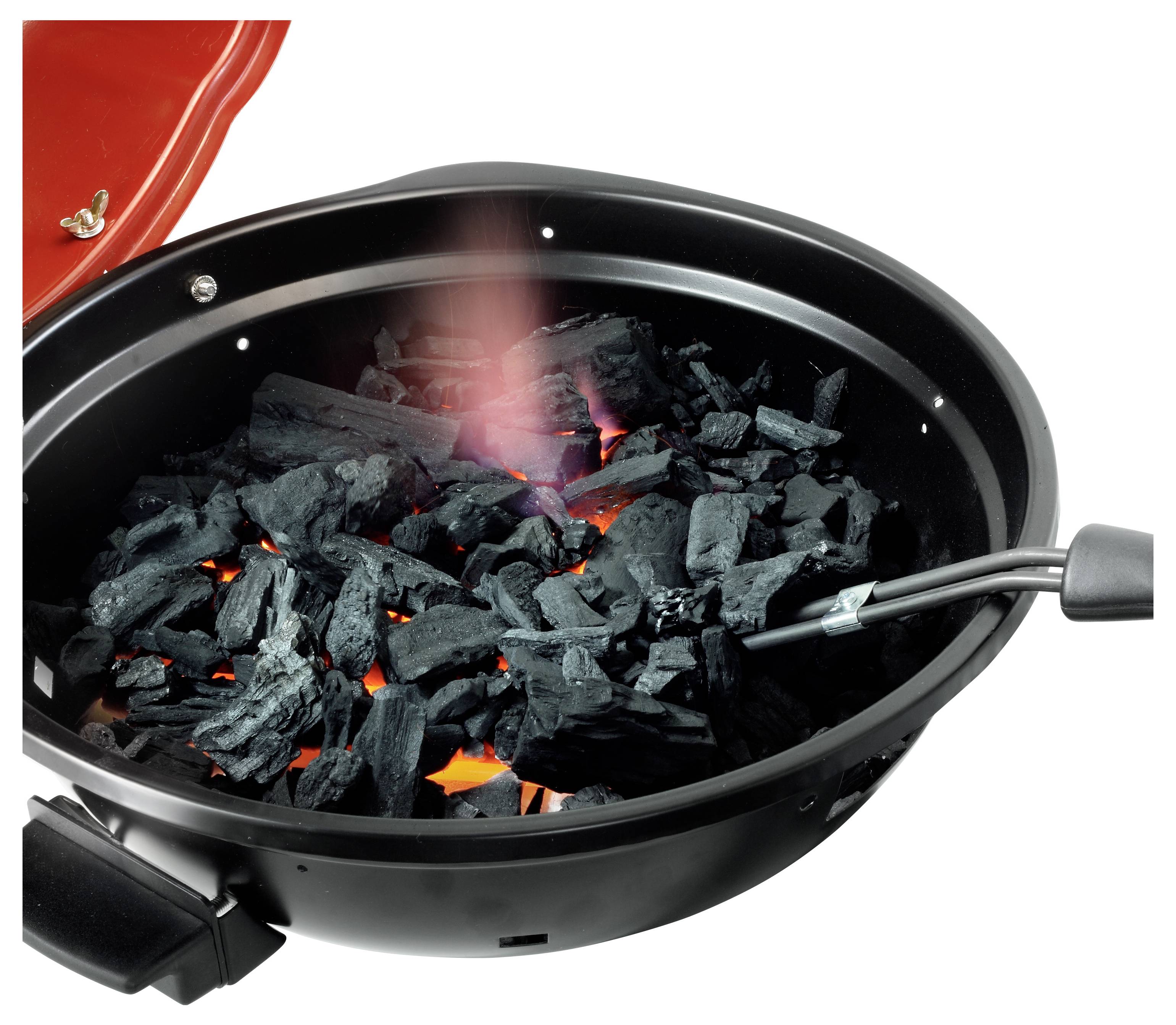 Pálení uhlí v černém grilu na grill, s červeným víkem otevřeným a zářícím uhlím viditelným uvnitř.