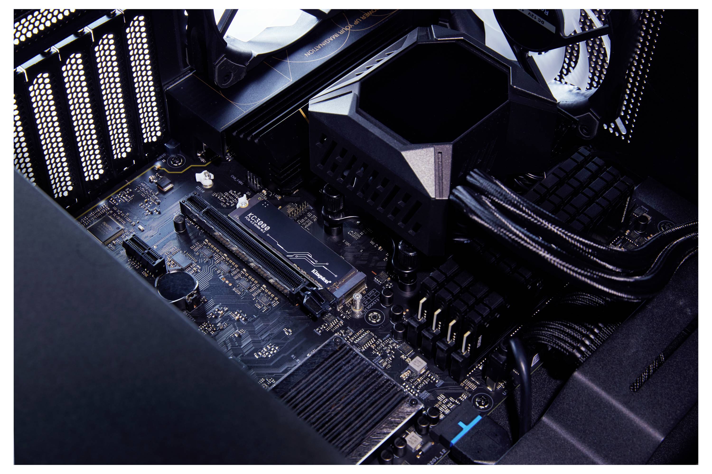 Detailní pohled na desku plošných spojů stolního počítače s velkým chladičem CPU, sloty pro RAM a napájecími kabely uvnitř pouzdra počítače.
