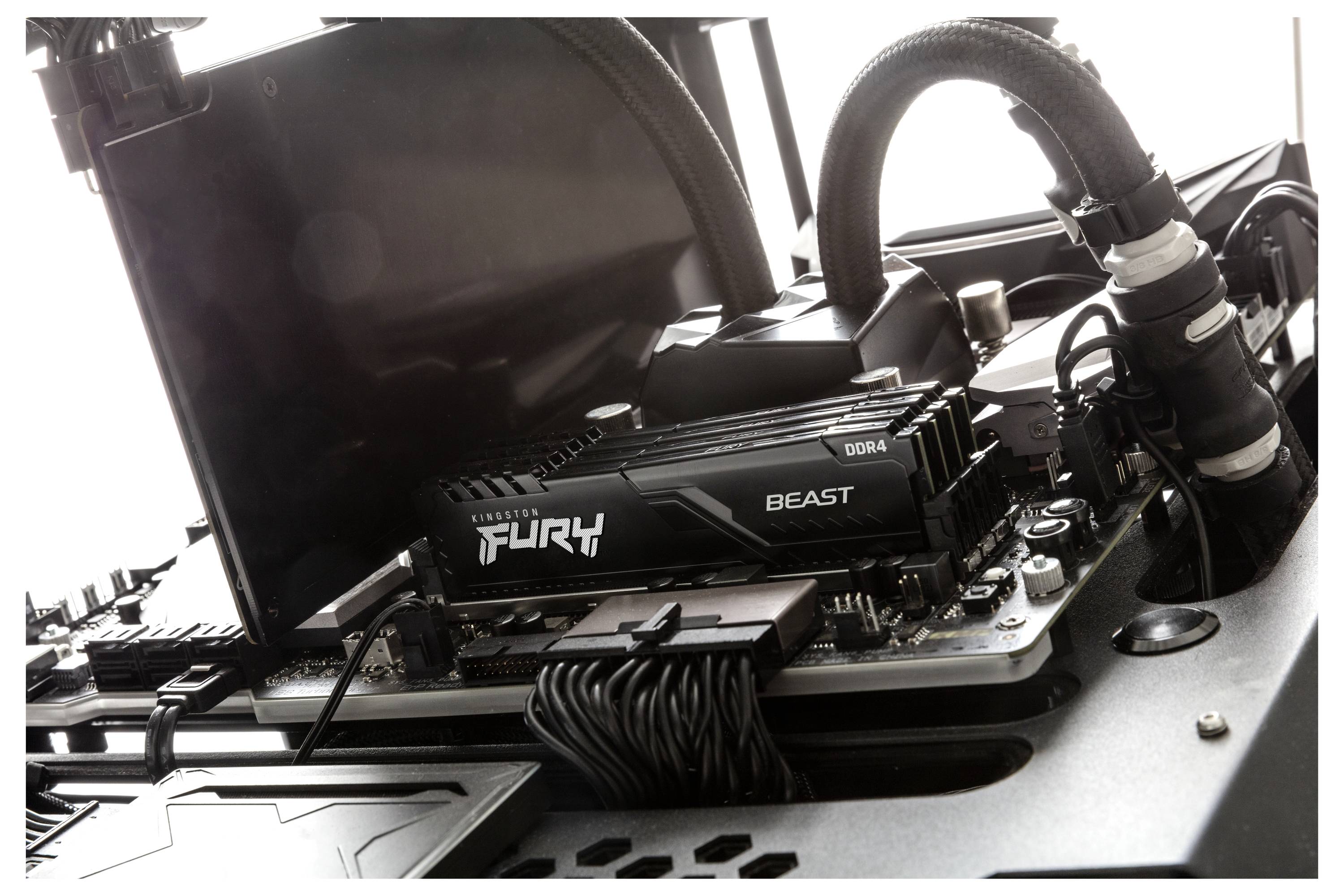 Detailní pohled na vlastní základní desku počítače s operační pamětí označenou „FURY Beast" a připojeným kapalinovým chladicím potrubím.