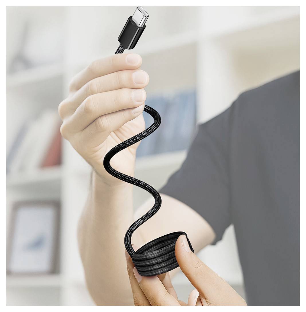 Osoba držící černý kabel USB-C, který je úhledně navinutý kolem šnury, zatímco drží konektorový konec.