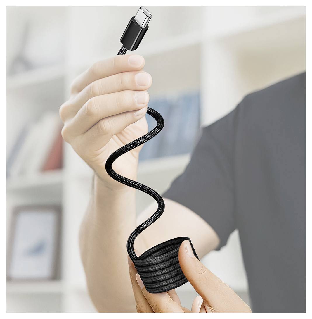 Osoba držící černý stočený kabel USB-C pro nabíjení, která ukazuje pružný spirálovitý kord a konec konektoru.