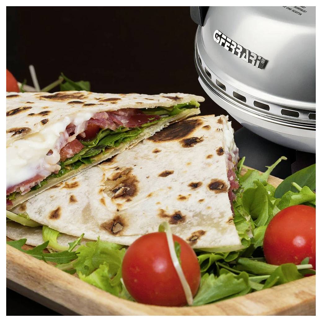 Grilovaná quesadilla na dřevěné desce s zeleninou a cherry rajčaty vedle nerezové grilovací lisovny.