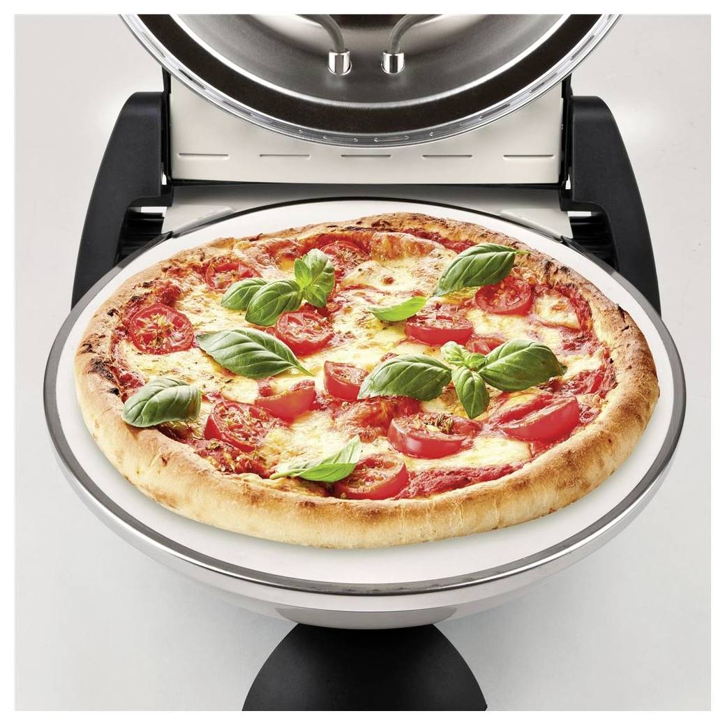 Pizza pečící se v kuchyňské pizzerie, posetá rajčaty a bazalkou.
