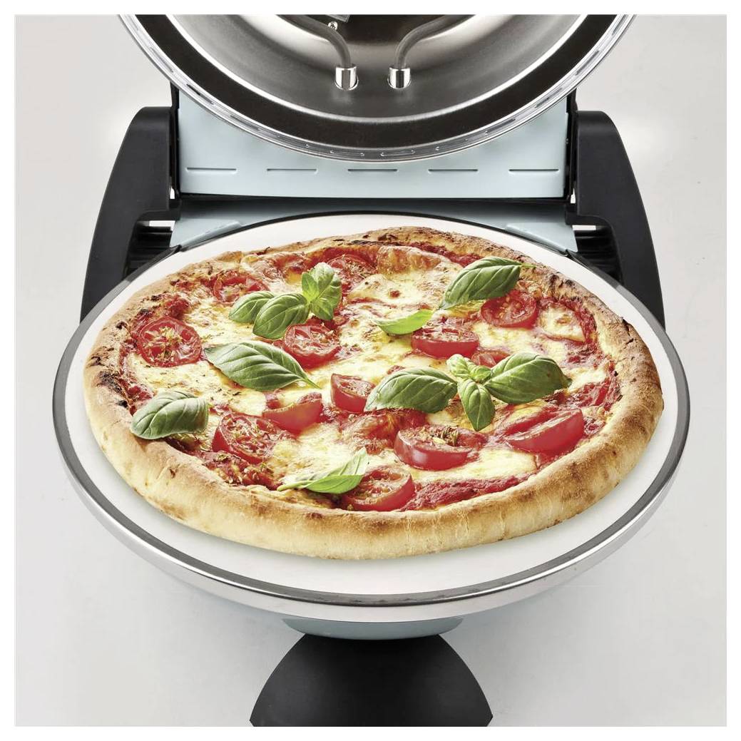 Pečení pizzy v stolním troubě s pizzou s rajčetem a bazalkou na rotující podnosů.
