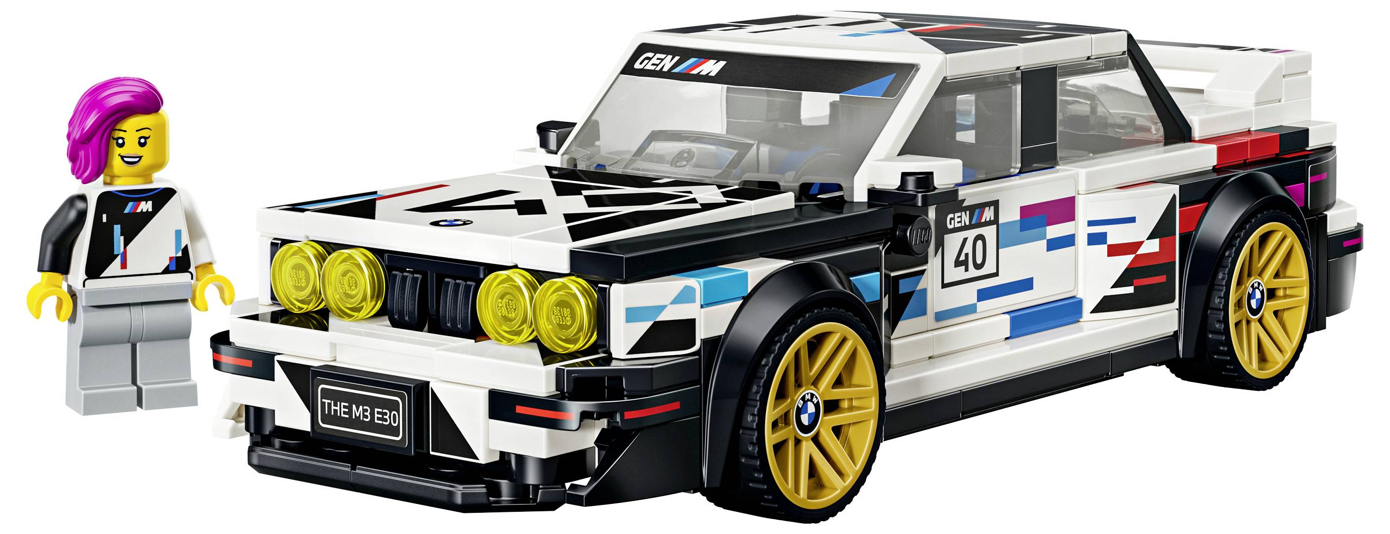 LEGO-stylový závodní vůz BMW se zlatými koly a čtyřmi žlutými předními světly, zobrazený vedle figurky řidiče na bílém pozadí.
