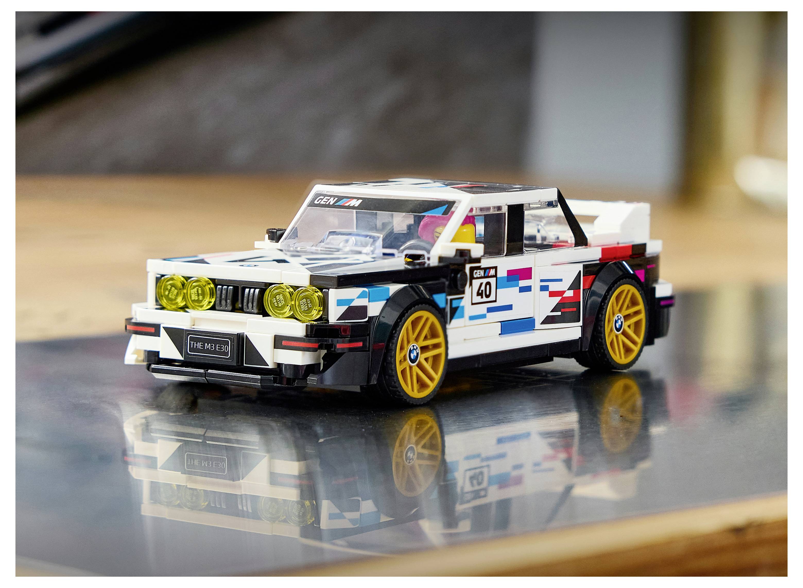 Bílý závodnický vůz LEGO se žlutými koly na reflexní ploše, zobrazen v bočném-předním pohledu v interiéru.