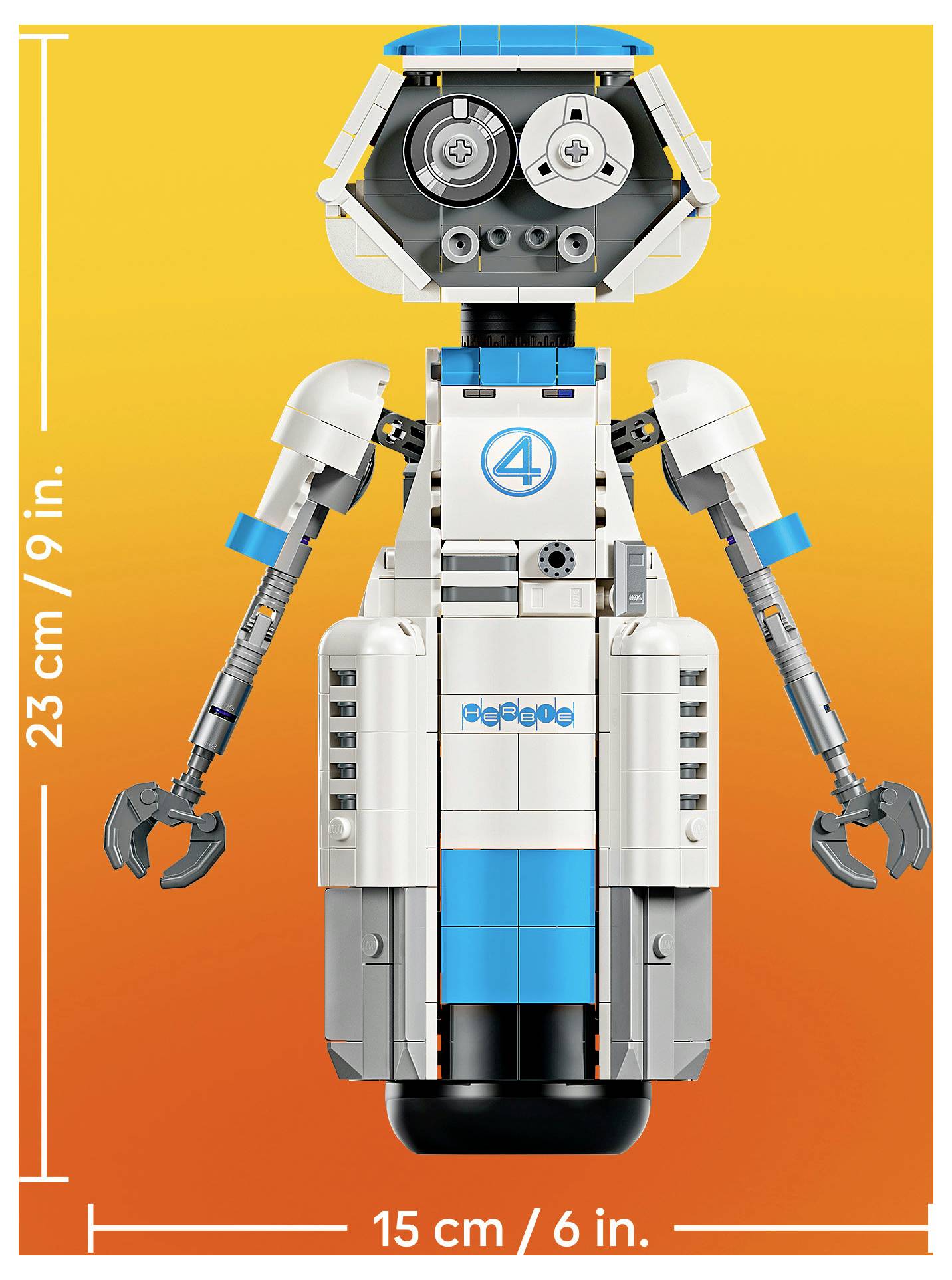 Přední pohled LEGO-stylové robotické figurky s drápy místo rukou na oranžovém pozadí, označené jako 23 cm/9 palců vysoké a 15 cm/6 palců široké.