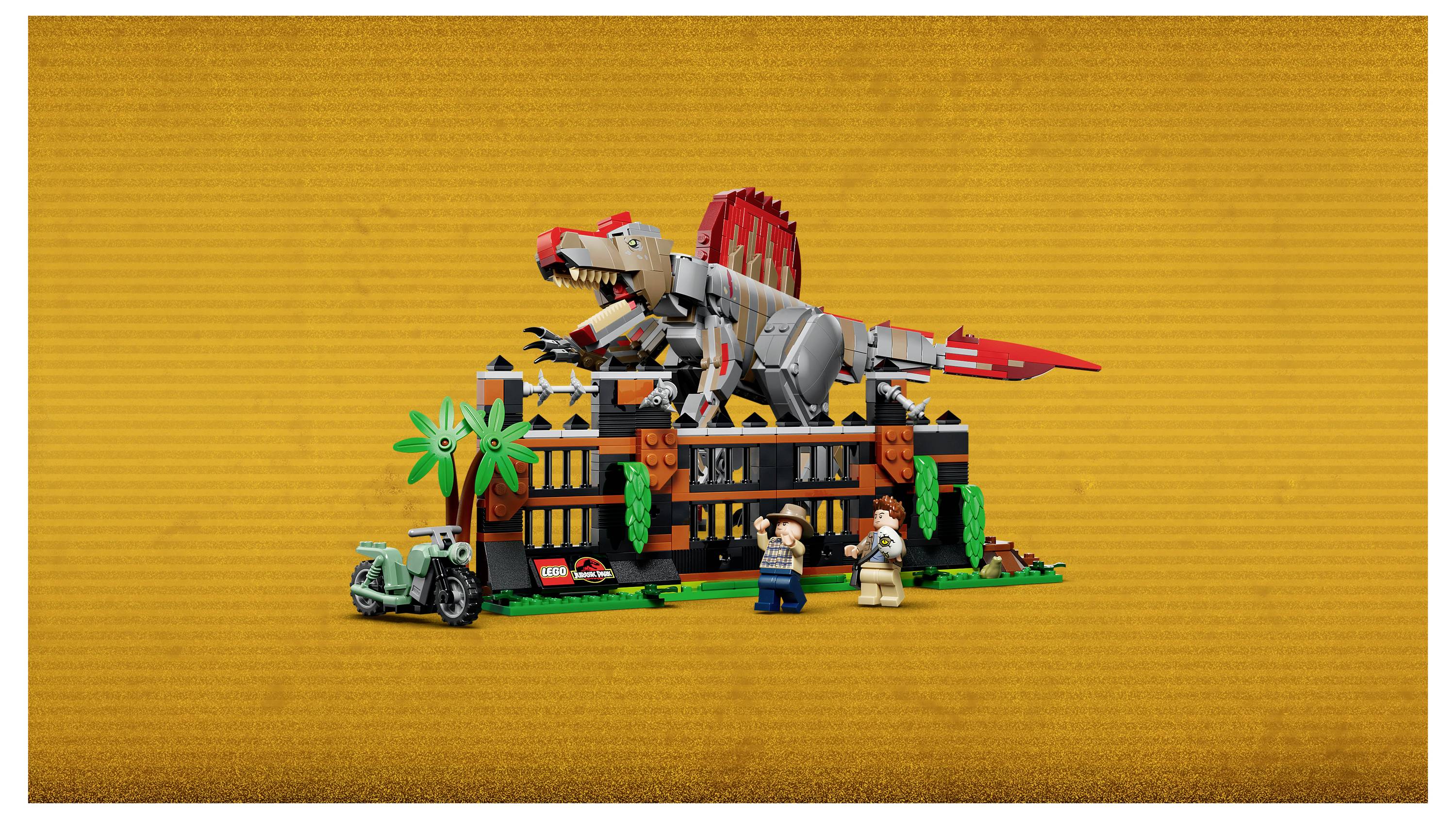 LEGO scéna s výstavou dinosaurů s velkým červeno-šedým dinosaurem na budově, palmami a dvěma minifigurkami vpředu.