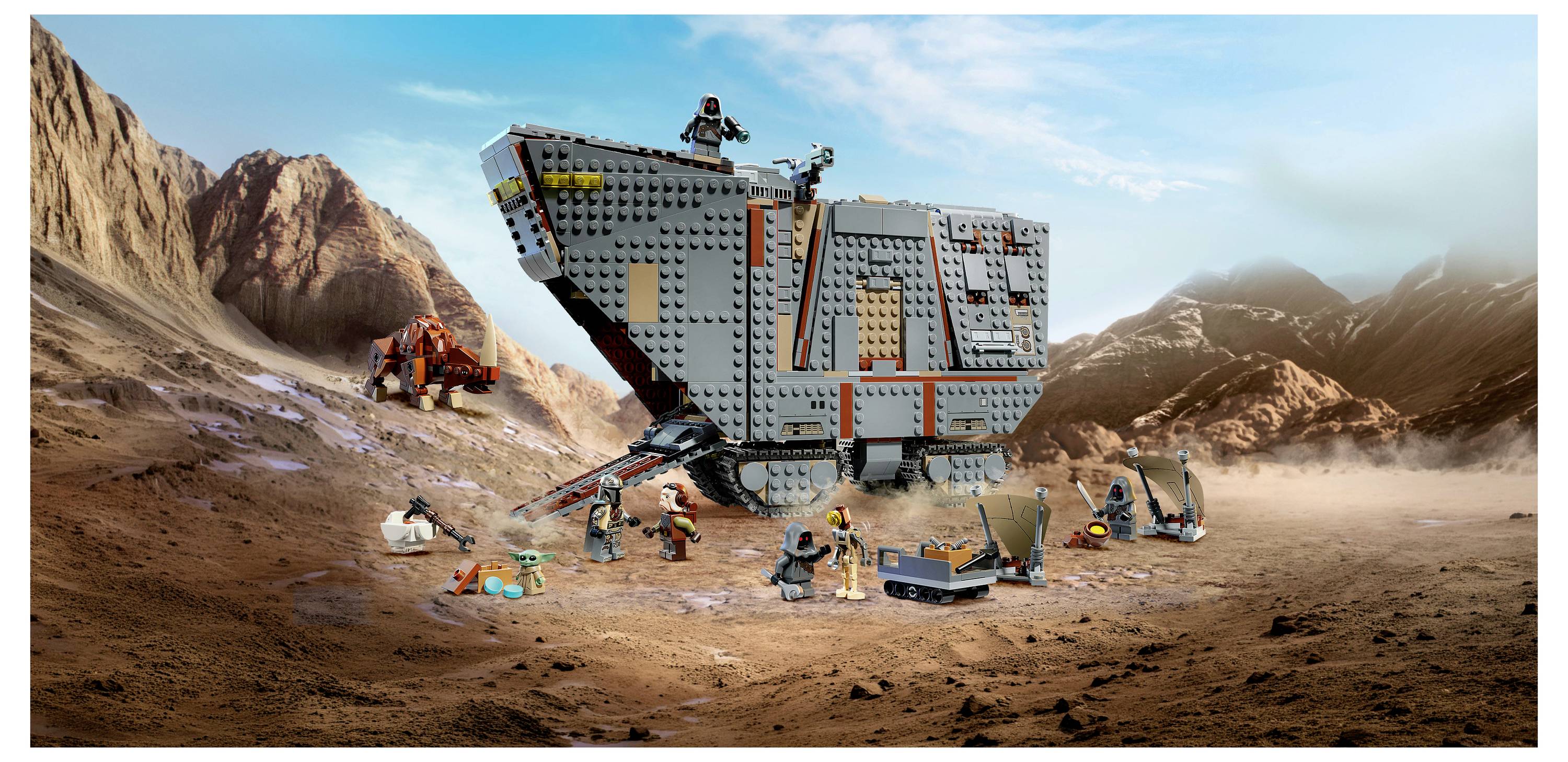 Scéna bitvy LEGO Star Wars s velkým šedým pancéřovaným vozidlem v skalnatém pouštním prostředí, obklopeným minifigurkami a malými bojovými vozidly uprostřed prachu a explozí.