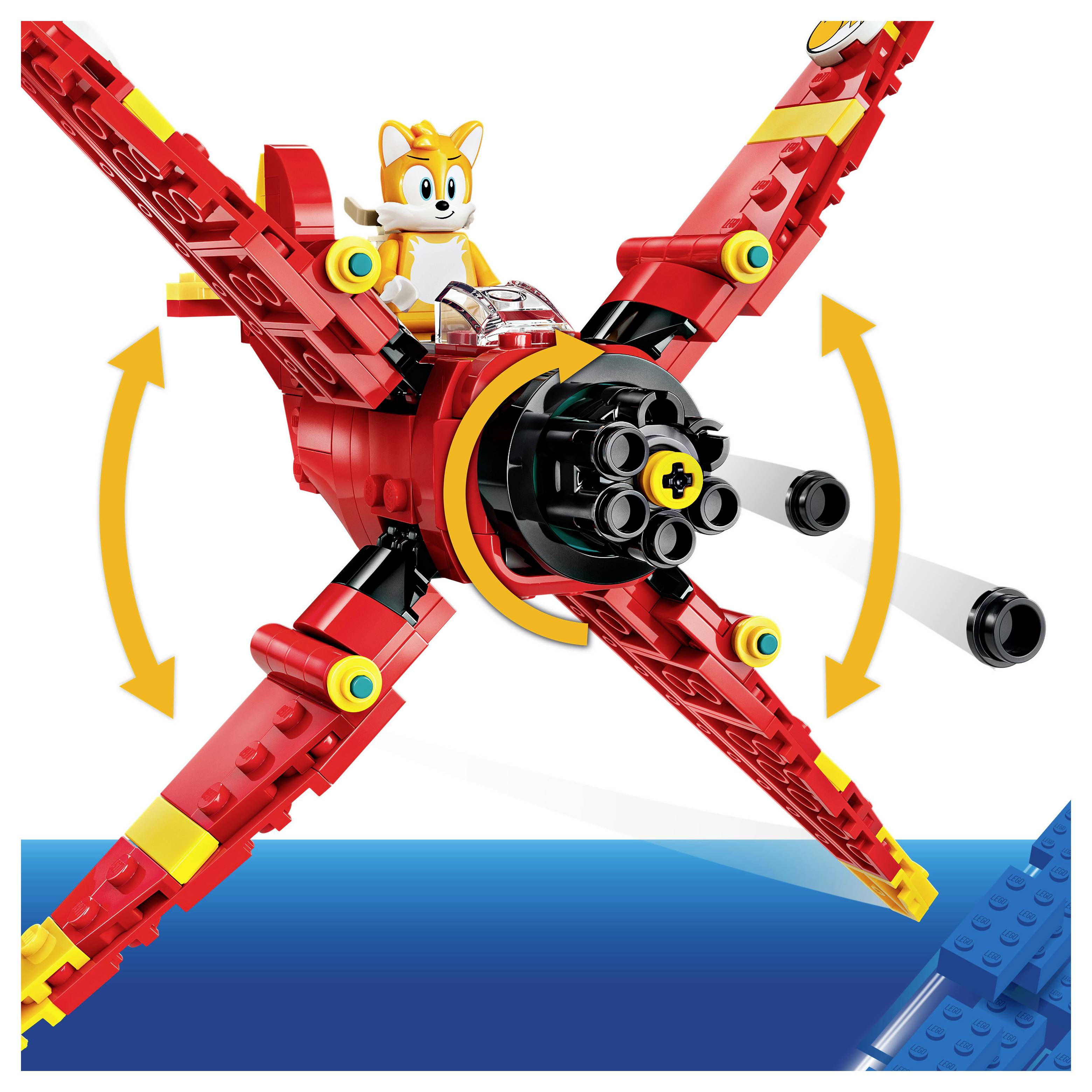 LEGO styl červeného letadla s figurkou Tailse, zobrazujícího rotující vrtuli a skládací křídla naznačená šipkami.