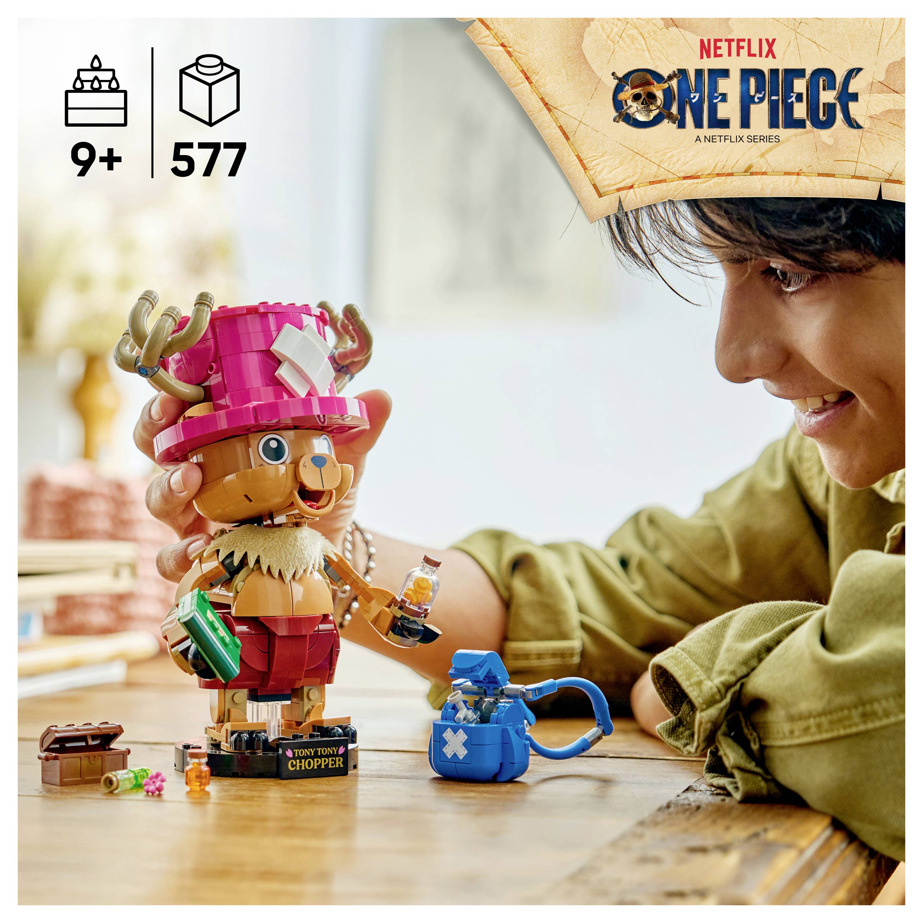 Dítě si hraje s LEGO One Piece Tony Tony Chopper stavebnicí a drobnými příslušenstvím na stole; obalová grafika ukazuje 'ONE PIECE' a věkové omezení 9+ s 577 kusy.
