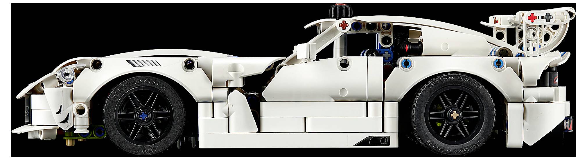 Bočný pohled na bílý závodní model automobilu ve stylu LEGO s exponovanými černými koly a detailními mechanickými součástkami na černém pozadí.