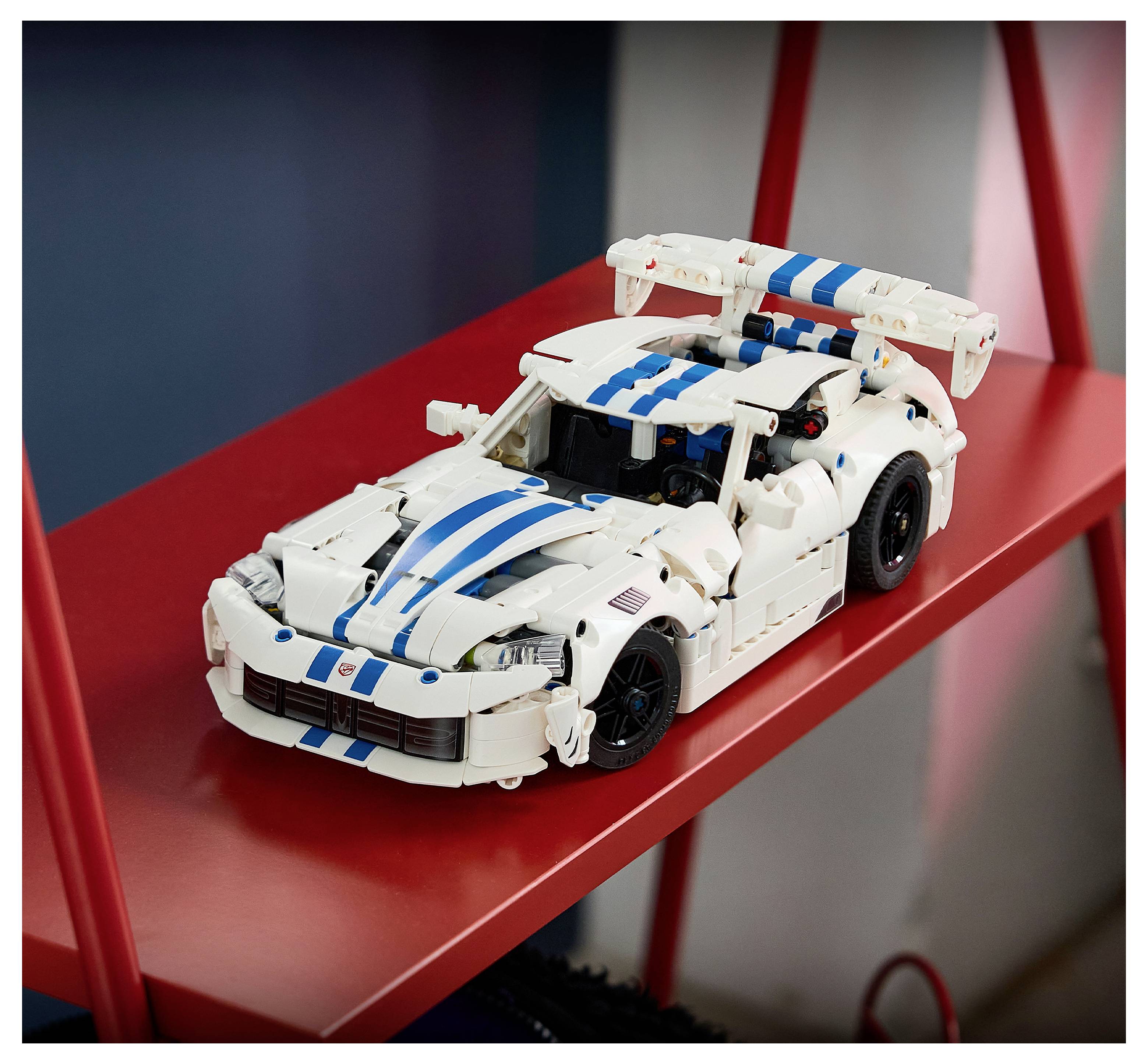 Bílé závodní auto LEGO s modrými pruhy na červené poličce, zobrazeno v tříčtvrtečném pohledu.