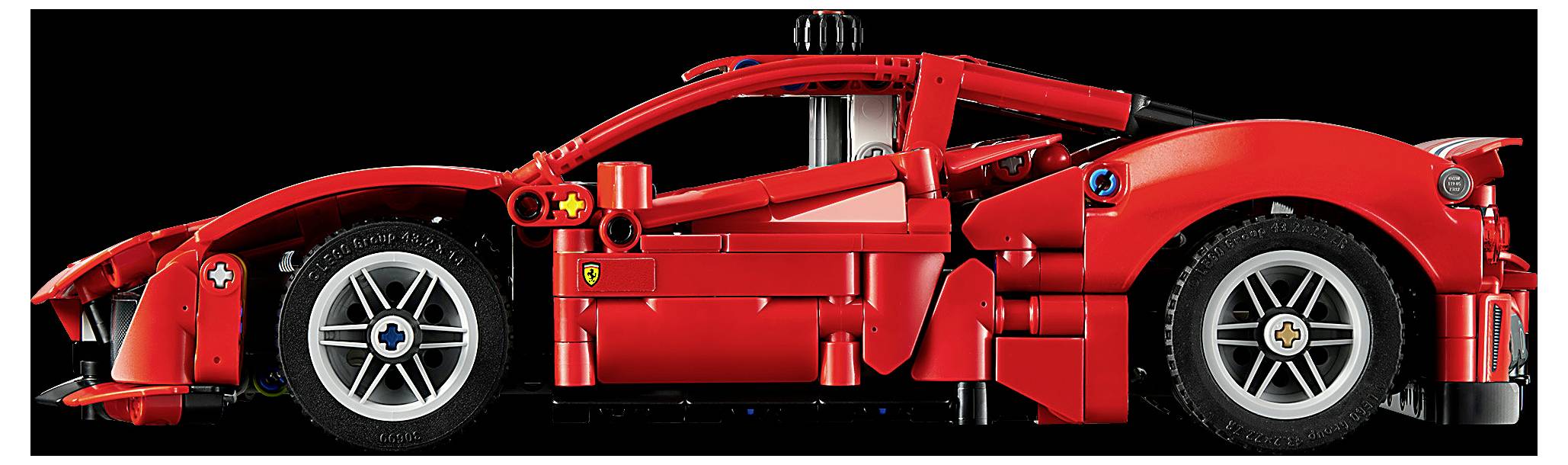 Boční pohled na lesklý červený formule 1 závodní vůz na černém pozadí, který zobrazuje jeho nízkou aerodynamickou karoserii a velká exponovaná kola.