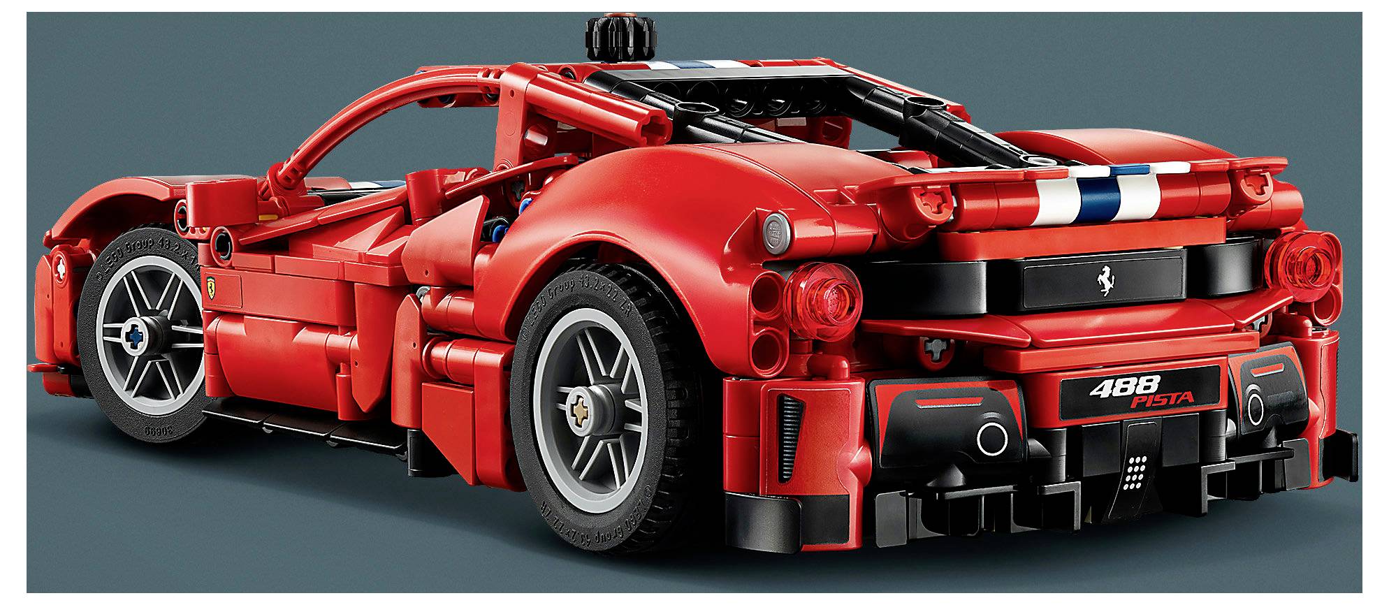 Zadní pohled na červený sportovní vůz Ferrari 488 Pista, zobrazený v obrázku ve stylu studia s černými závodními pásy a viditelnými detaily zadní části.