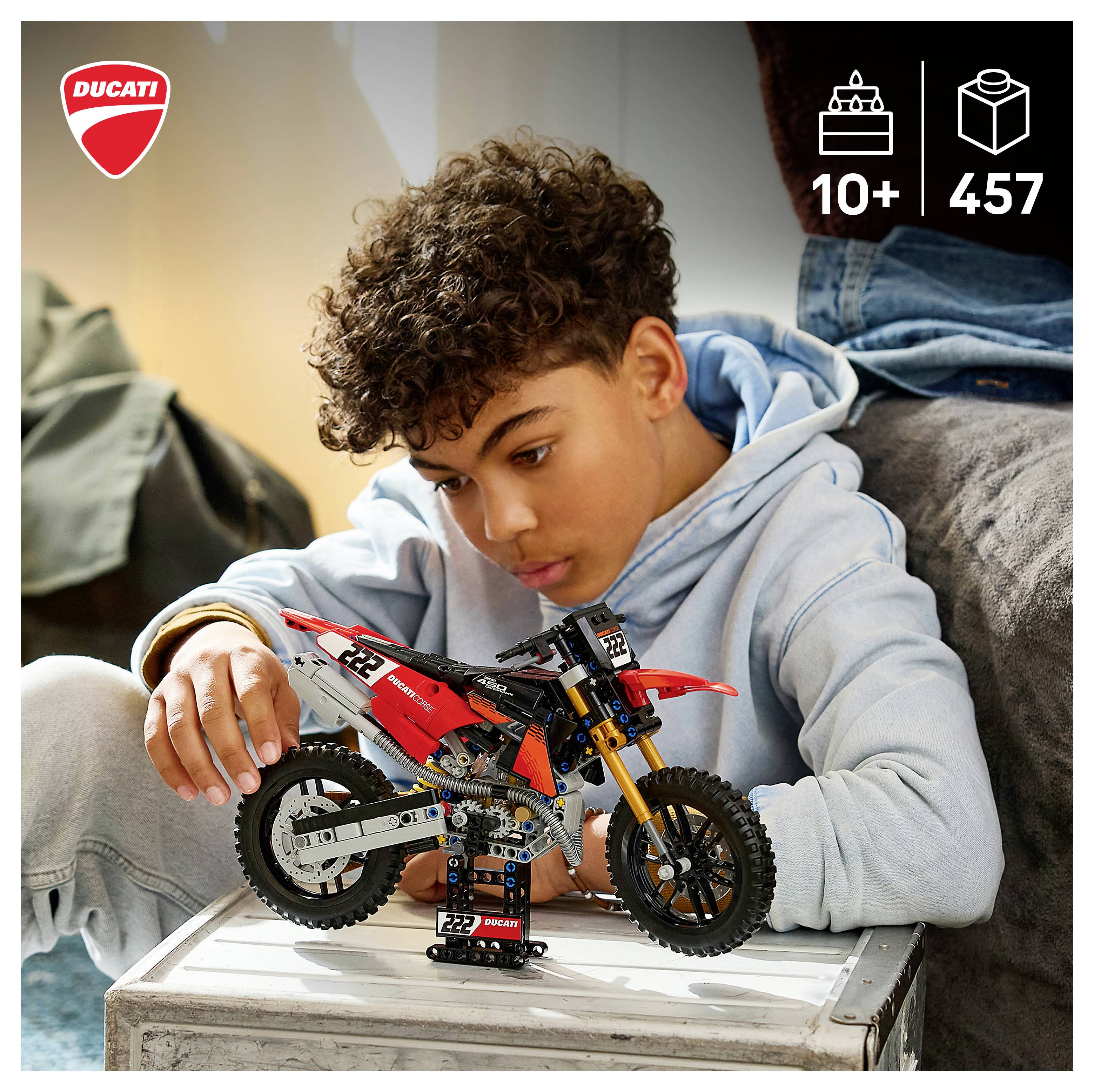 Chlapec skládající modelovou sadu motocyklu Ducati na stole s zobrazením '10+' a počtu dílů '457'.