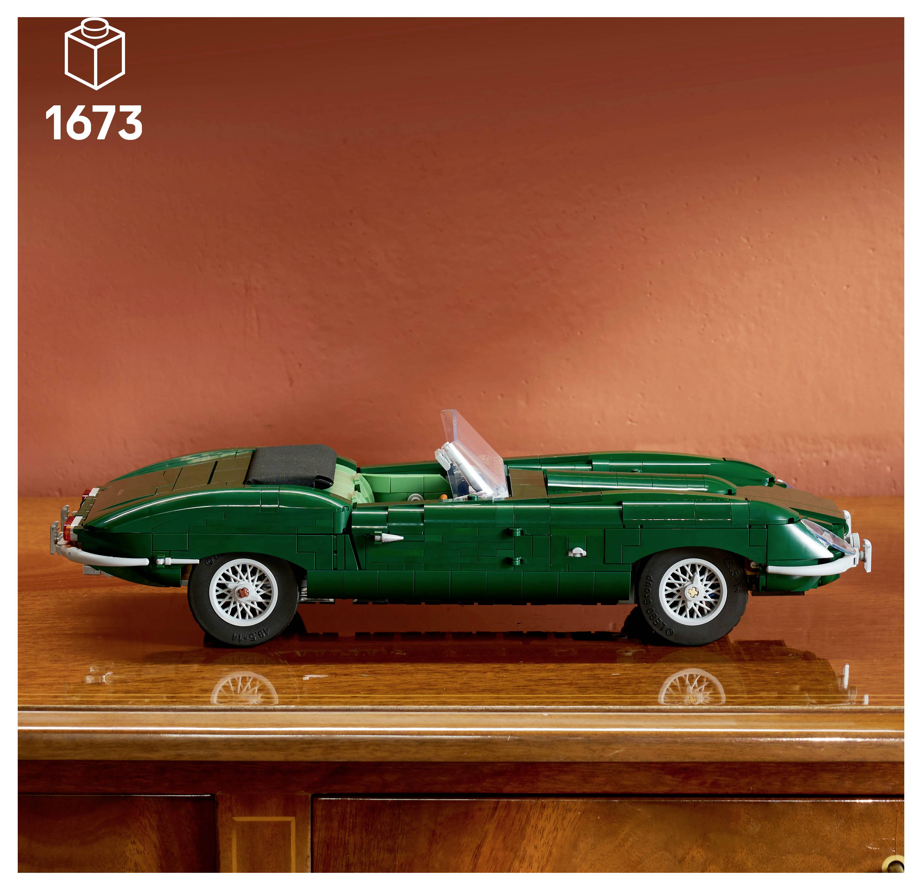 LEGO-stylový zelený vintage kabřiolet zobrazený v profilu na dřevěné ploše, s označením 1673 v rohu.