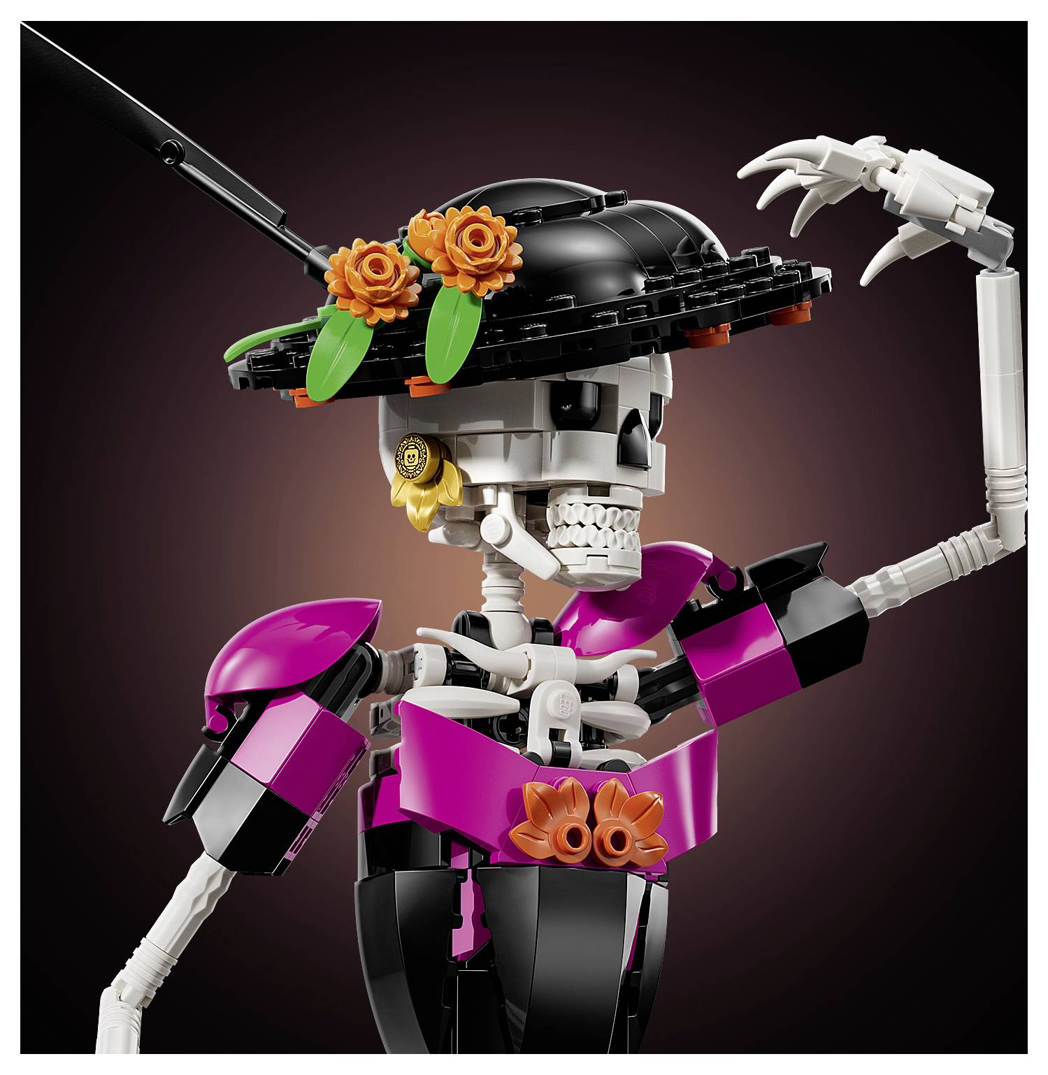 Stylizovaná figurka kostry LEGO v černém klobouku s oranžovými květinami, oblečená v purpurově-černém outfitu a zvedající jednu ruku.