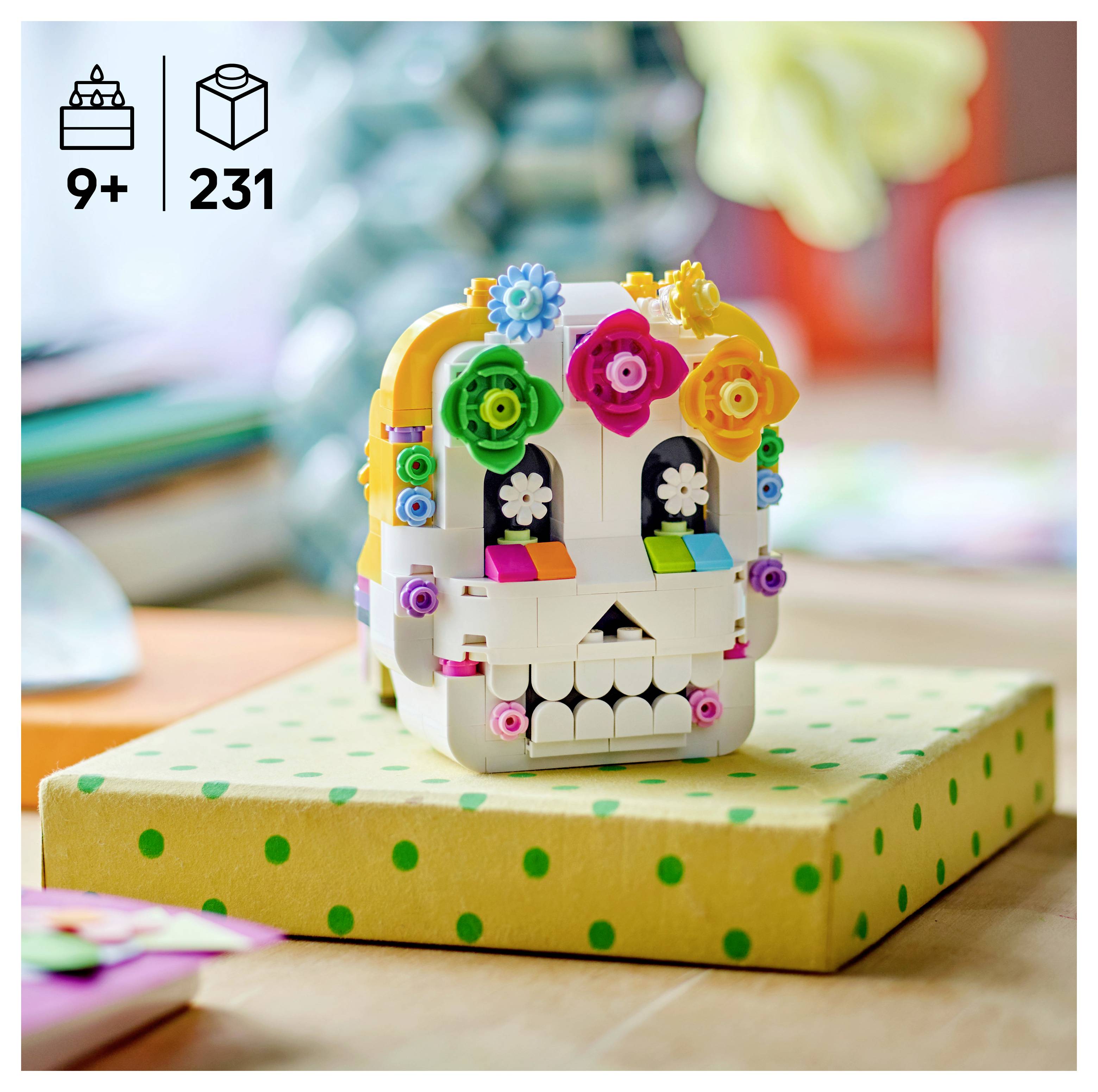 Barevná lebka ve stylu LEGO s květinovou výzdobou na puntíkovaném podstavci, označena '9+' a '231' kusů.