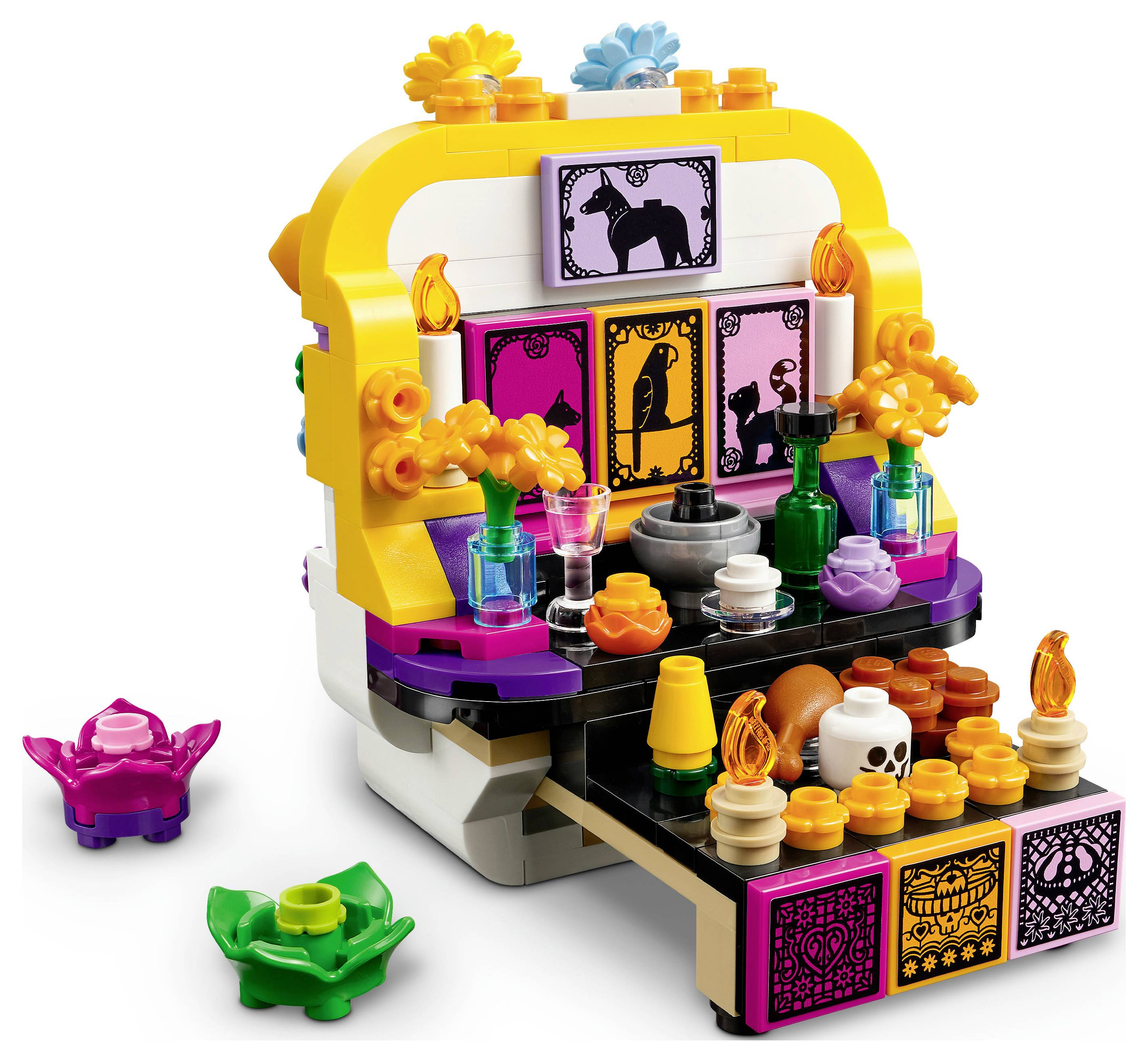 Barevný miniaturní oltář ve stylu LEGO se zvířecími siluetovými dlaždicemi, svícemi, květinami, nápoji, lebkou a jídlem na černožluté předváděcí podstavci.