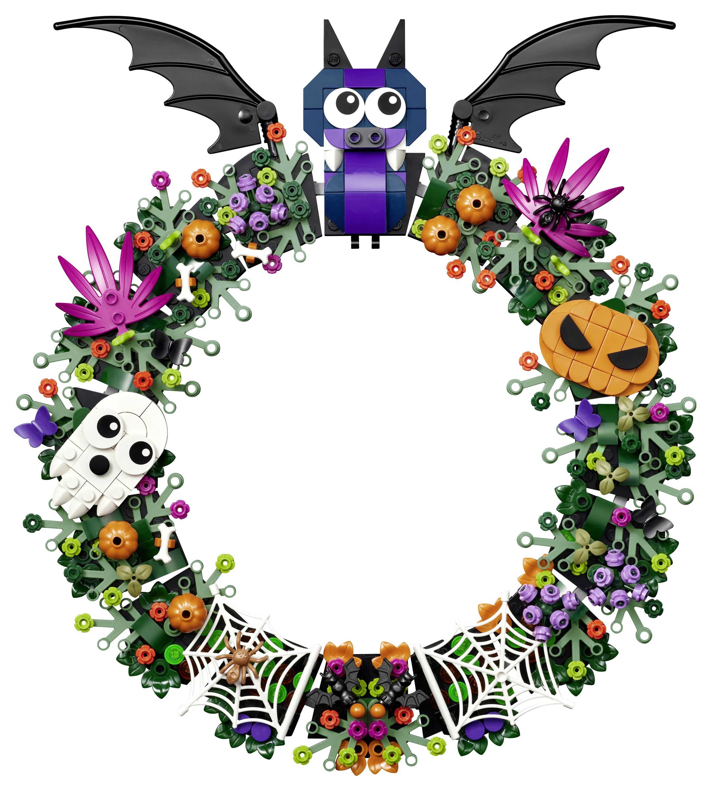 Halloweenský věnec s netopýrem nahoře, fialovými květinami, oranžní dýní, lebkou, pavučinami a pavokem na kruhovém zeleném vinnému rámci.