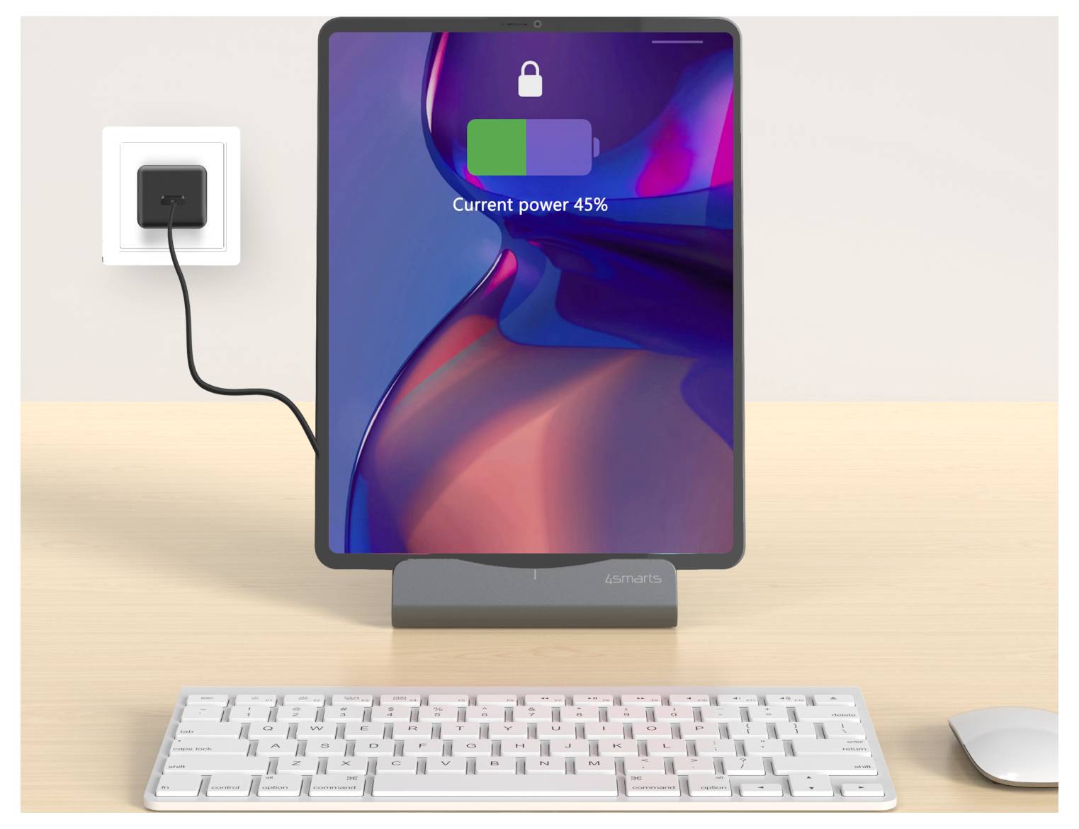 Tablet na dokovací stanici nabíjející se na stole, zobrazující ikonu zámku a "Aktuální výkon 45%"; klávesnice a myš vpředu, kabel zapojený do zásuvky na stěně.