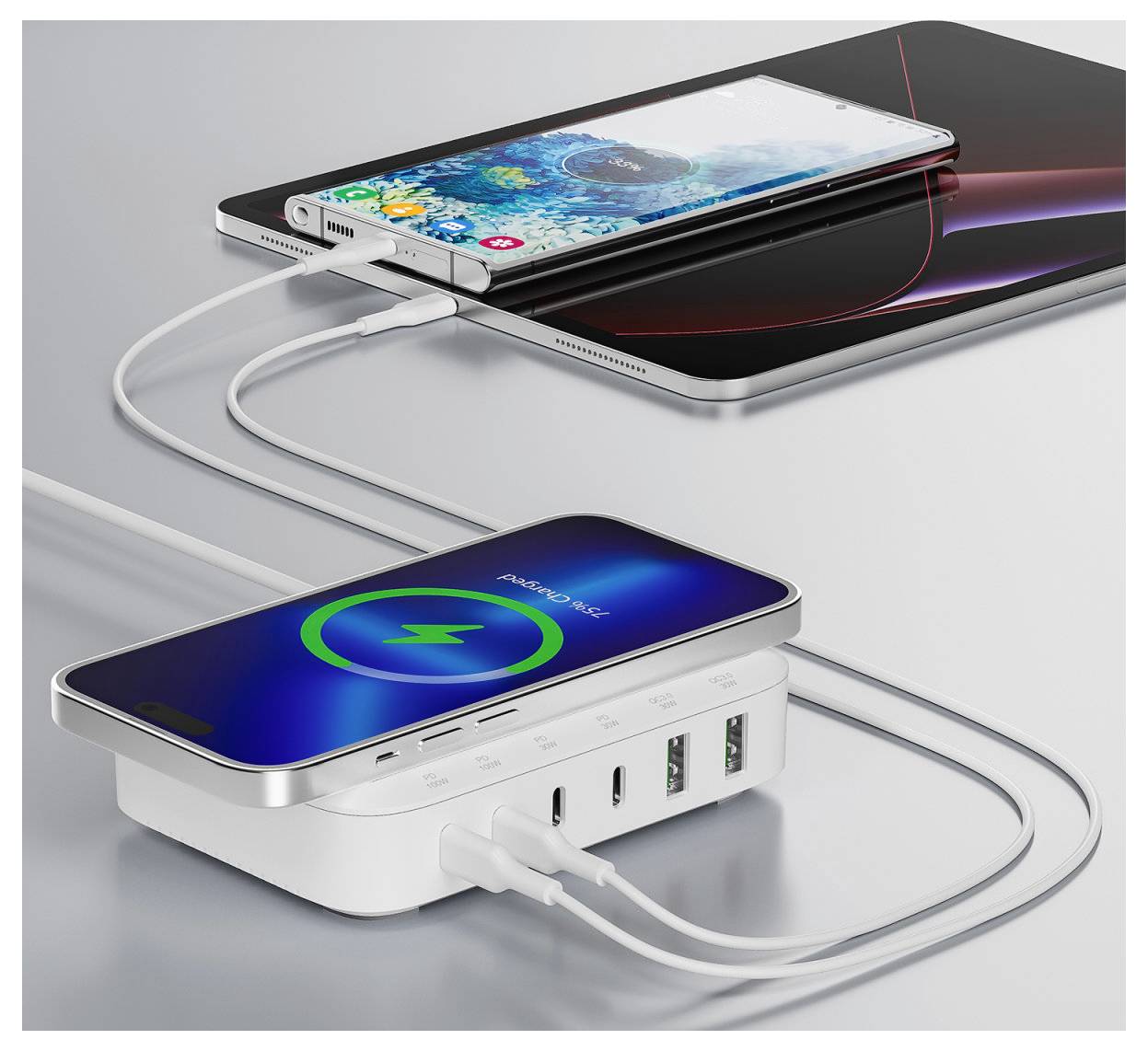 Dva smartphony se nabíjejí z bílé multivýstupové powerbanky s připojenými kabely; jeden telefon zobrazuje na obrazovce ikonu bezdrátového nabíjení.