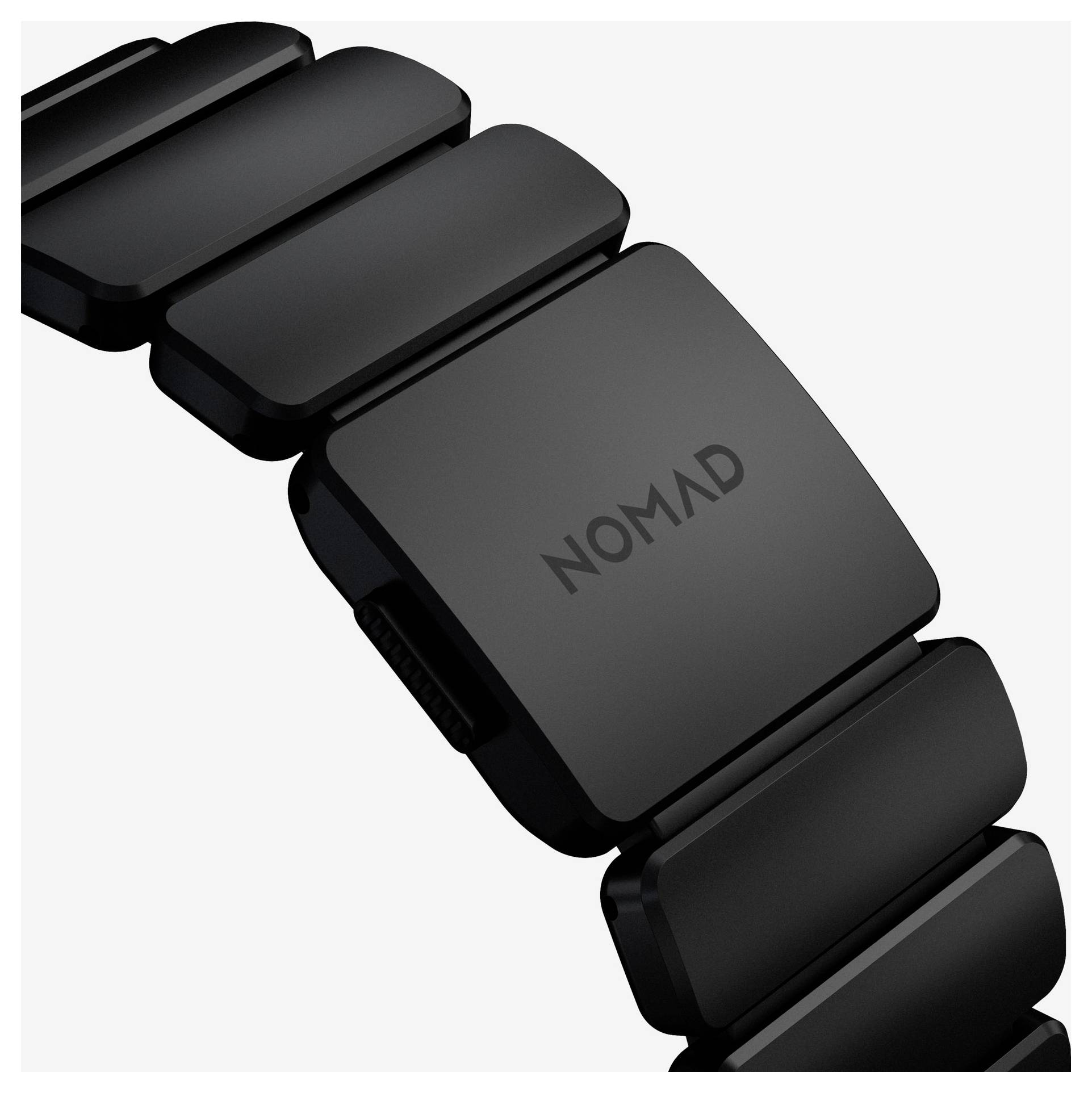 Detailní pohled na černý segmentovaný pásek chytrých hodinek s matným spájem označeným "NOMAD" na bílém pozadí.