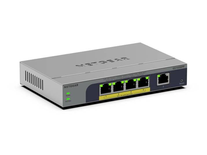 Síťový přepínač Netgear Ethernet s pěti rozsvícenými porty LAN a jedním portem uplink, zobrazený v šedé kovové skříni pro stolní počítače na bílém pozadí.
