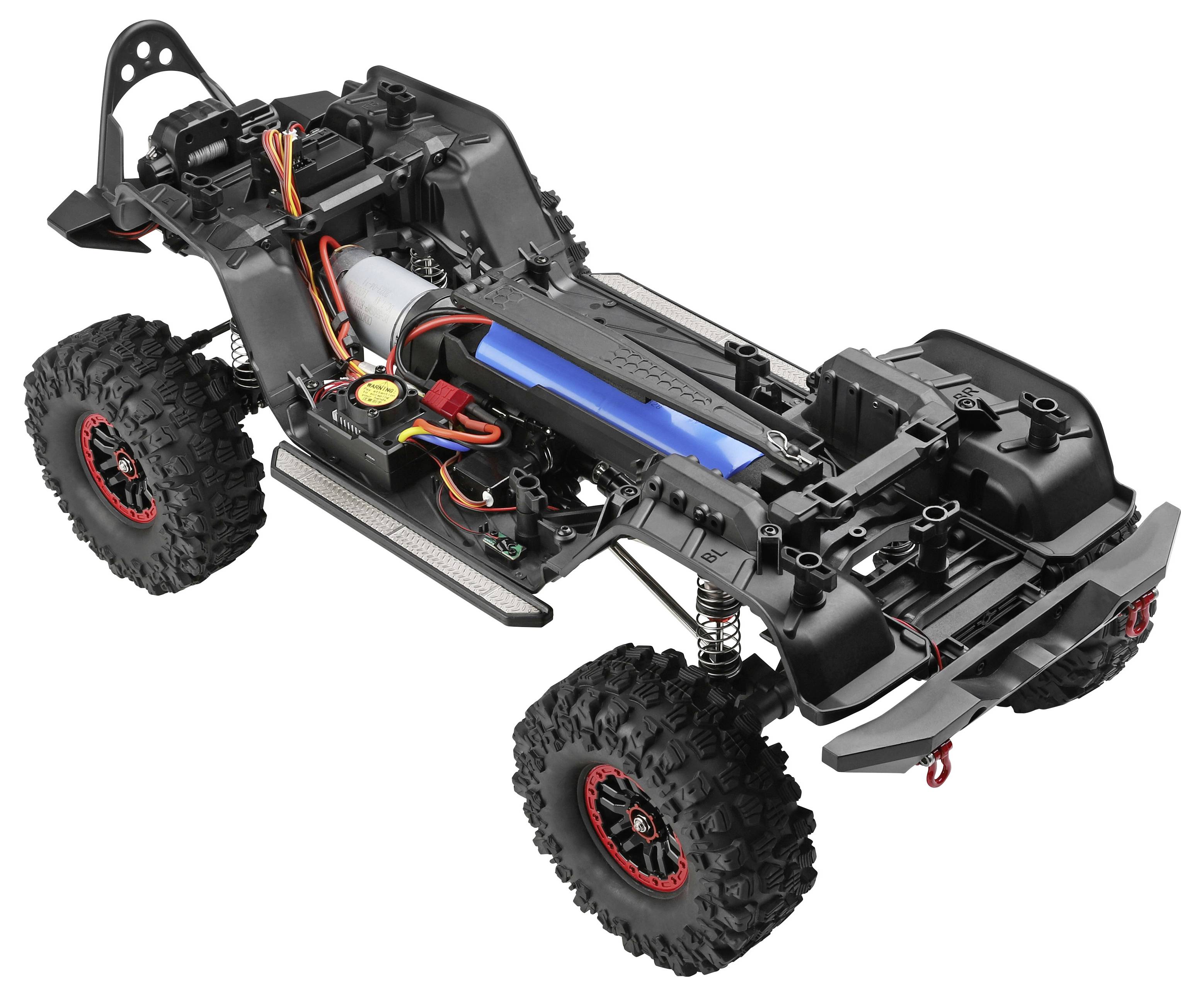 Částečně sestavený podvozek terénního RC automobilu s velkými drásavými pneumatikami, exponovaným motorem, paketou baterií a odpružením na bílém pozadí.