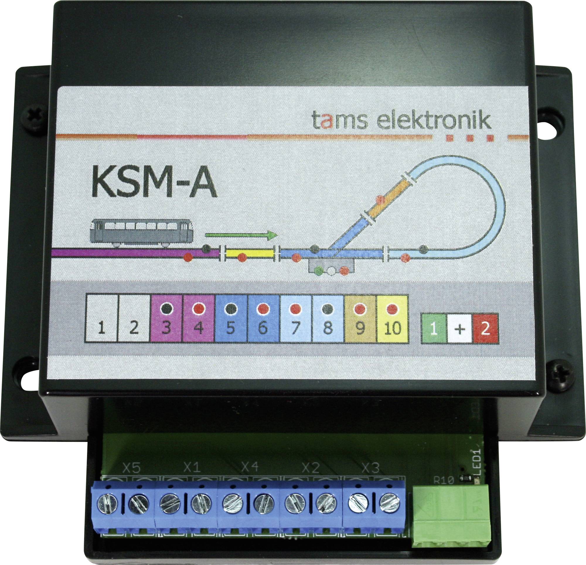Fotografie řídící jednotky kolejiště Tams Elektronik KSM-A modelu s popsaným schématem tratě, očíslovanými tlačítky výstupu a šroubovacími svorkovnicovými připojeními.
