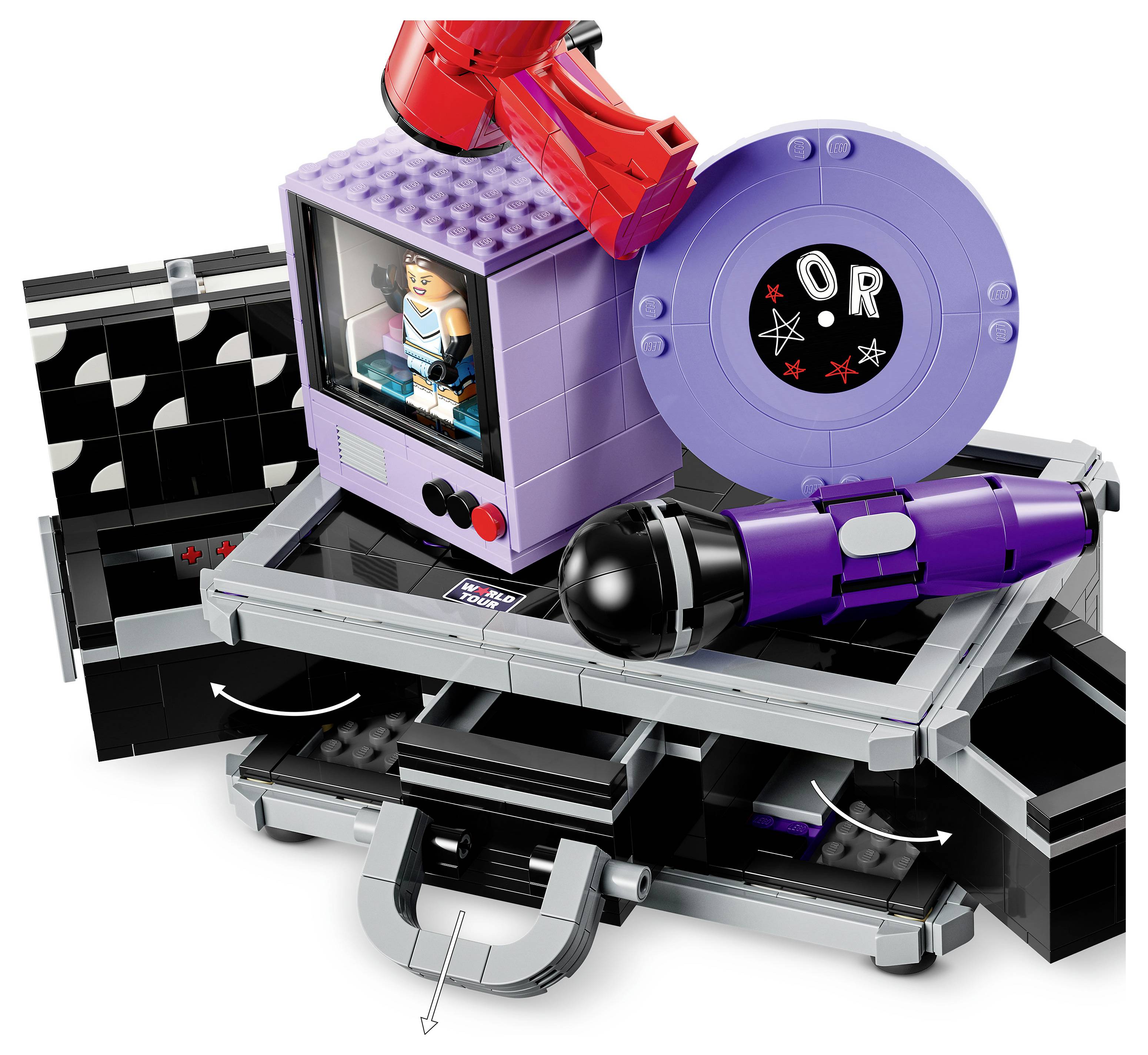 LEGO-podobné hračkové vozidlo se sedícím řidičem, velkými fialovými koly a červeným robotickým ramenem na otáčivé platformě.