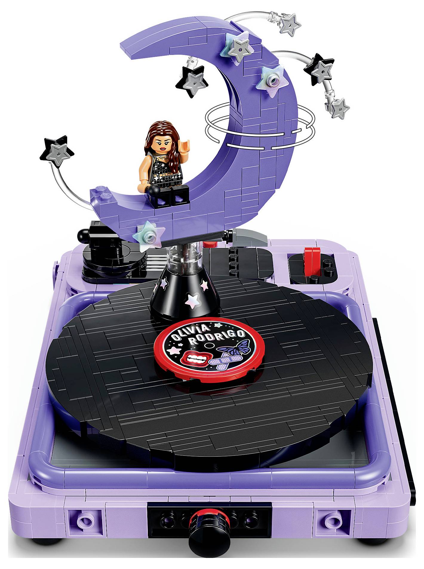 Hračkový gramofon s figurkou ve stylu LEGO, která sedí na fialové srpovité měsíci obklopené hvězdami, nad vinylovou deskou označenou "Olivia Rodrigo".