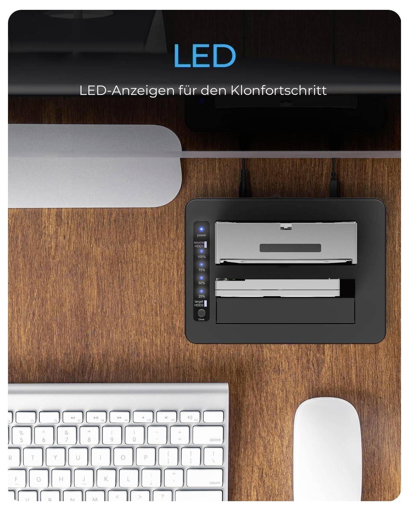 Nastavení stolu s klávesnicí, myší a dokovací stanicí vedle stojanu monitoru; text čte „LED" a „LED-indikátory pro průběh klonování" na dřevěném povrchu.