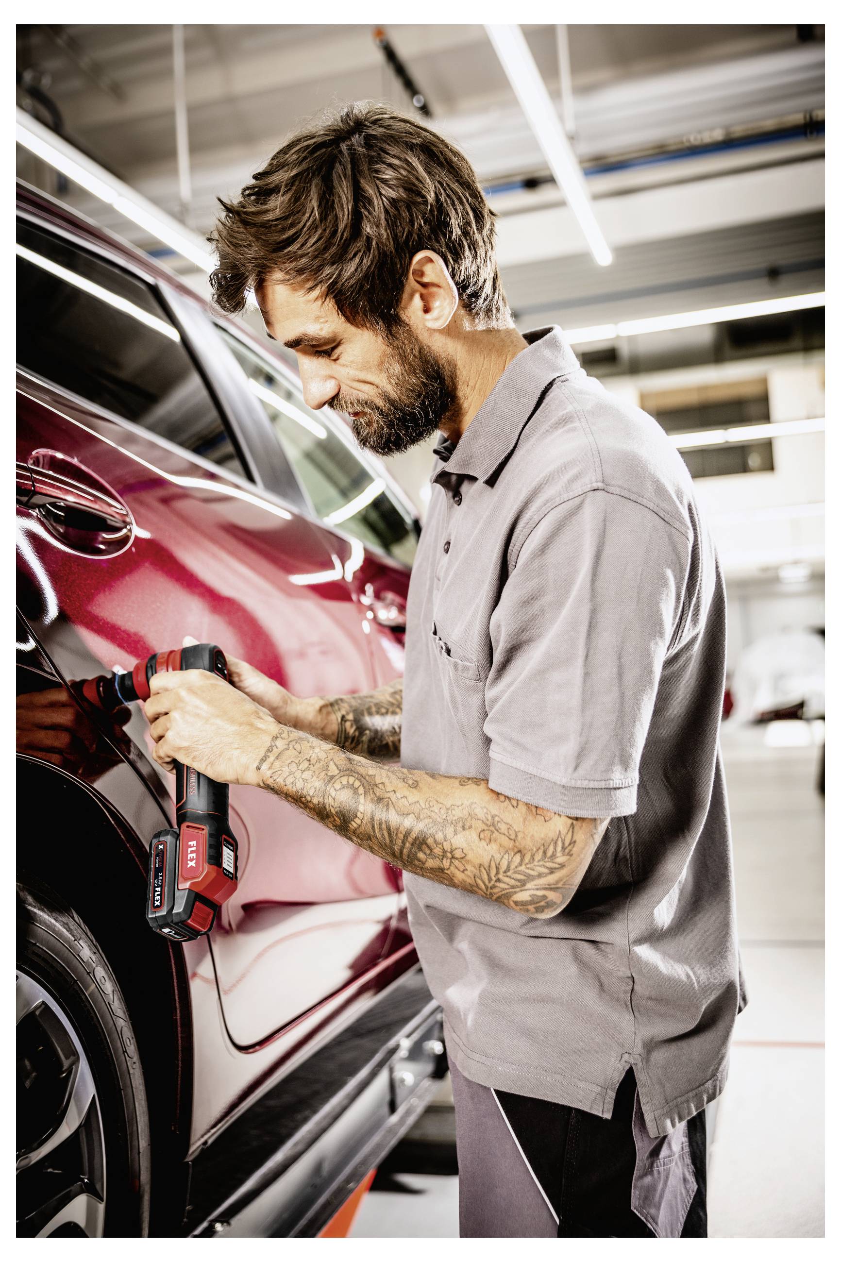 Mechanik leštící červený vůz SUV v autoprodejna s bezdrátovým lešticím nástrojem