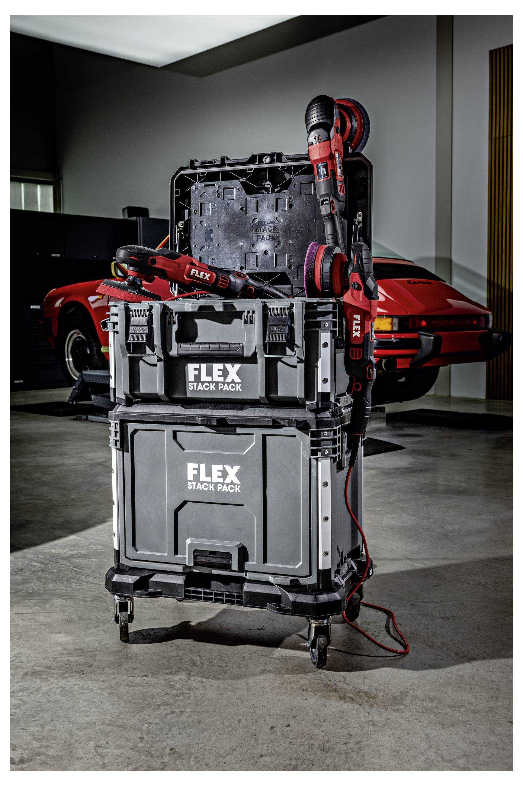 Skládané FLEX Stack Pack kufry na skladování nářadí s červeným bezdrátovým vrtákem a pilou na napájení připevněné, zobrazené v garáži s červeným sportovním autem vzadu.