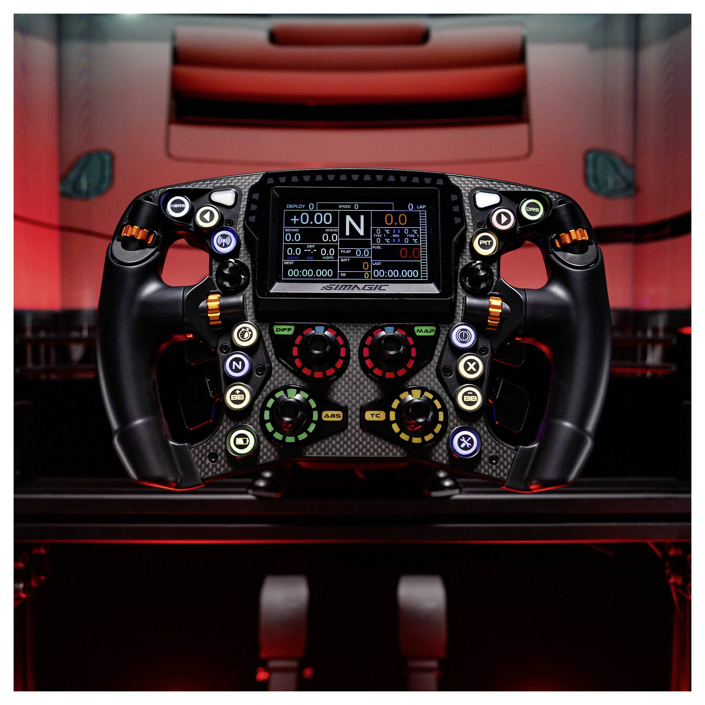 Detailní záběr na volant Formule 1 s digitálním displejem a barevnými ovládacími tlačítky, namontovaný v kokpitu osvětleném červeným světlem.