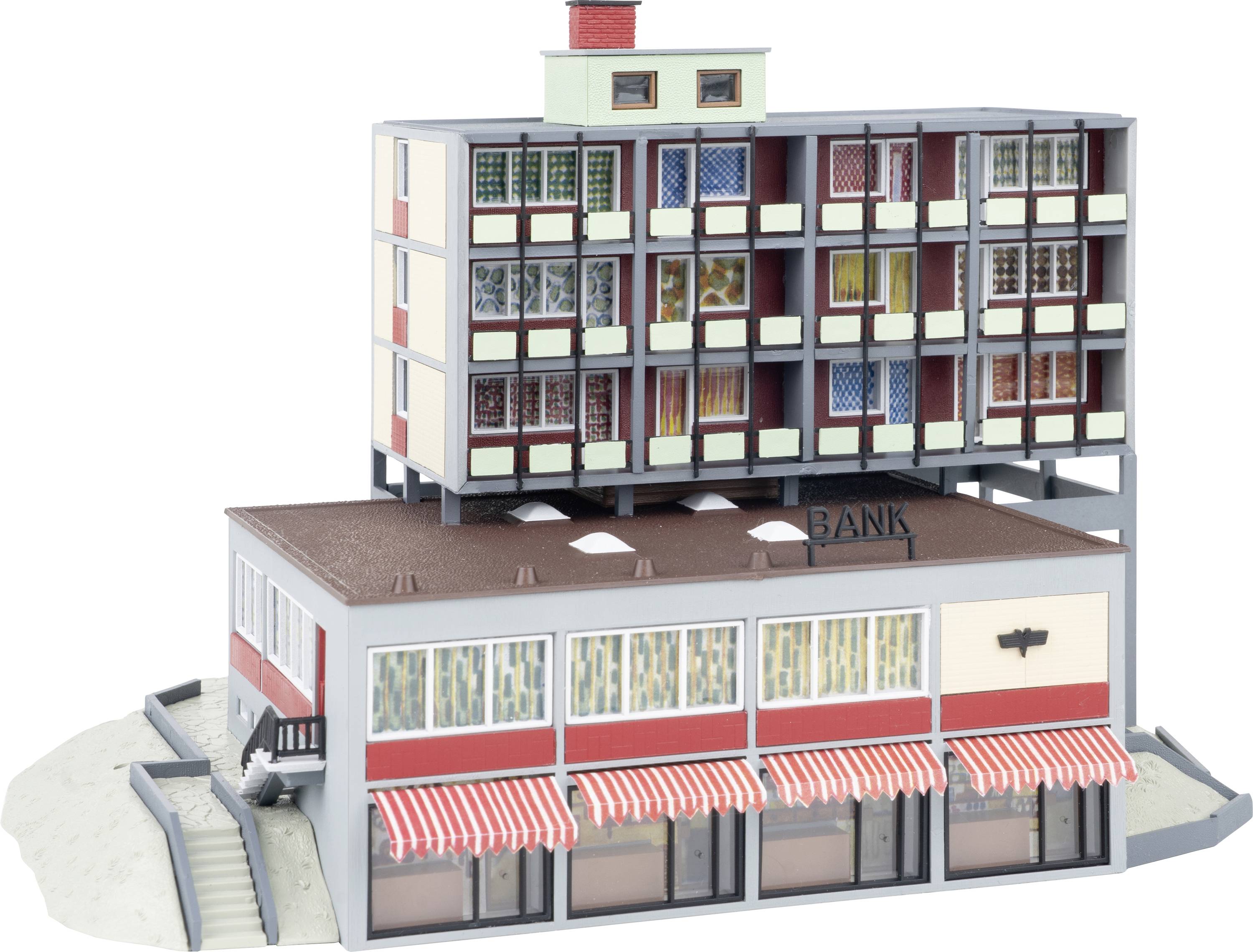 Model malé bankovní budovy s pruhovanými markýzami, která je zakončena vícepatrním bytovým domem, prezentovaný jako architektonická miniatura.