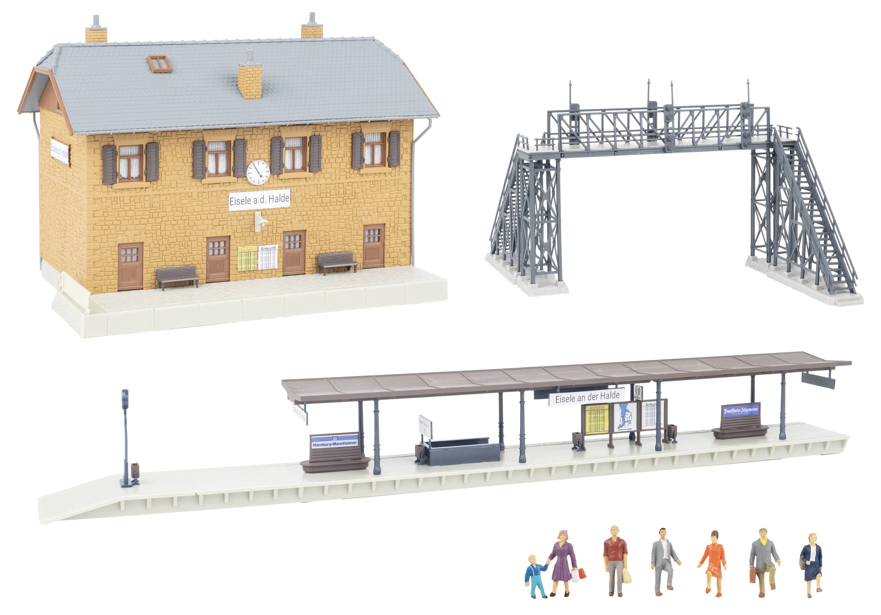 Modelová železniční scéna se stanicí označenou „Eisle a. d. Helle", kovový signální most, krytá perona, lampa, lavičky a figurky miniaturních lidí.