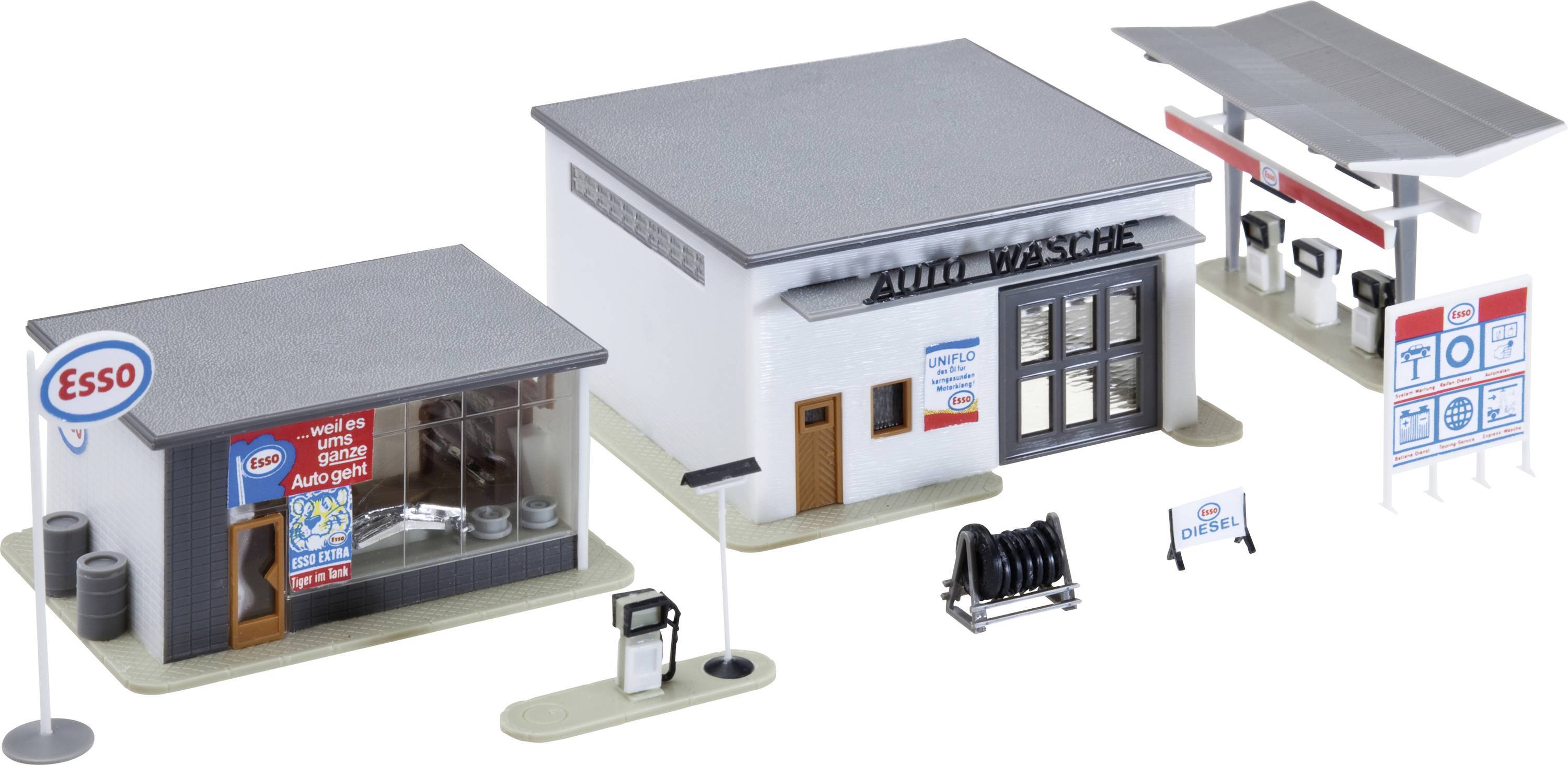 Miniaturní model benzínové čerpací stanice Esso se servisní garáží, hlavní budovou a stříškou čerpacích pump, prezentovaný jako diorama v měřítku.