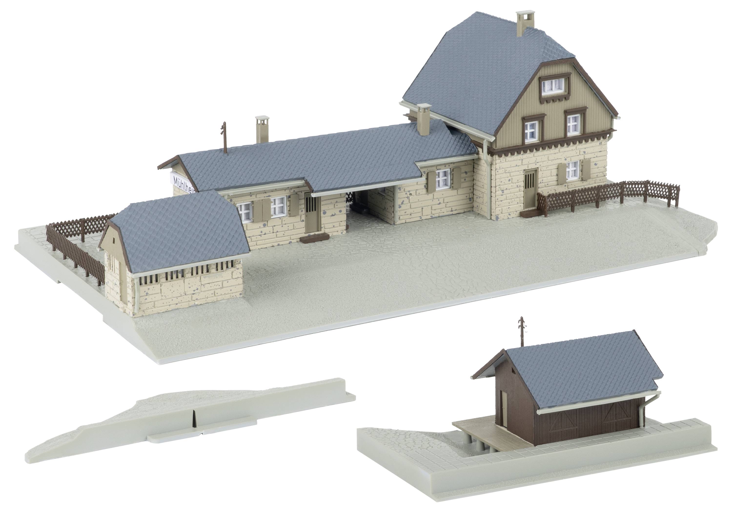 Architektonický model béžového domu s modrou střechou na šedé podstavě, plus dva oddělené menší stavební prvky zobrazené níže.