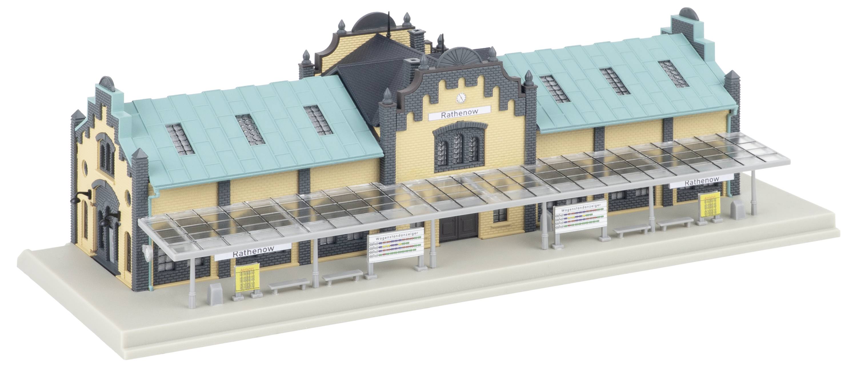 Architektonický model krémově-modrozelené železniční stanice s krytou plošinou zastřešení na základně pro vystavení.