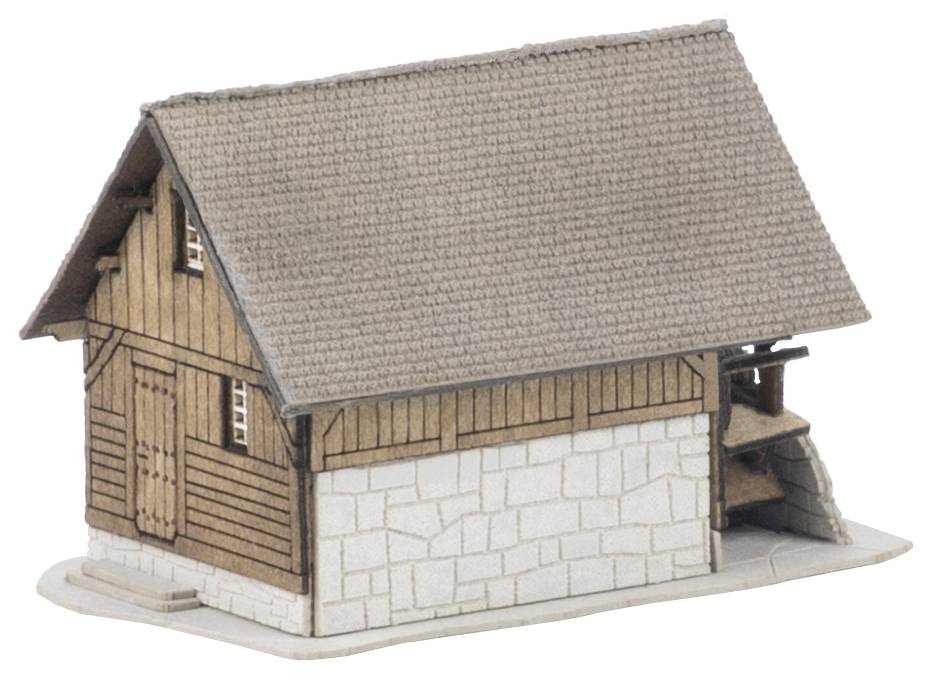 Malý model venkovského dřevěného domu se strmou střechou krytou šindelem a kamenným spodkem, znázorněný na bílém pozadí.