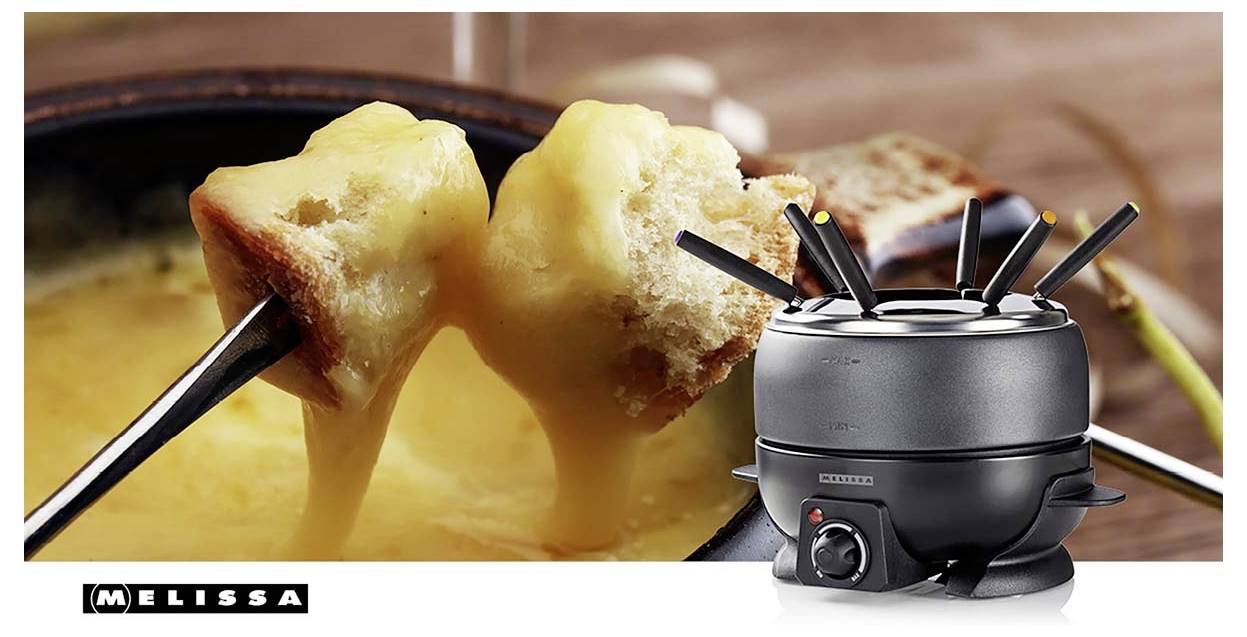Sýrové fondue s kostkami chleba na vidličkách vedle stolního hrnce na fondue, zobrazující scénu namáčení v rozpuštěném sýru a přenosný hořák.
