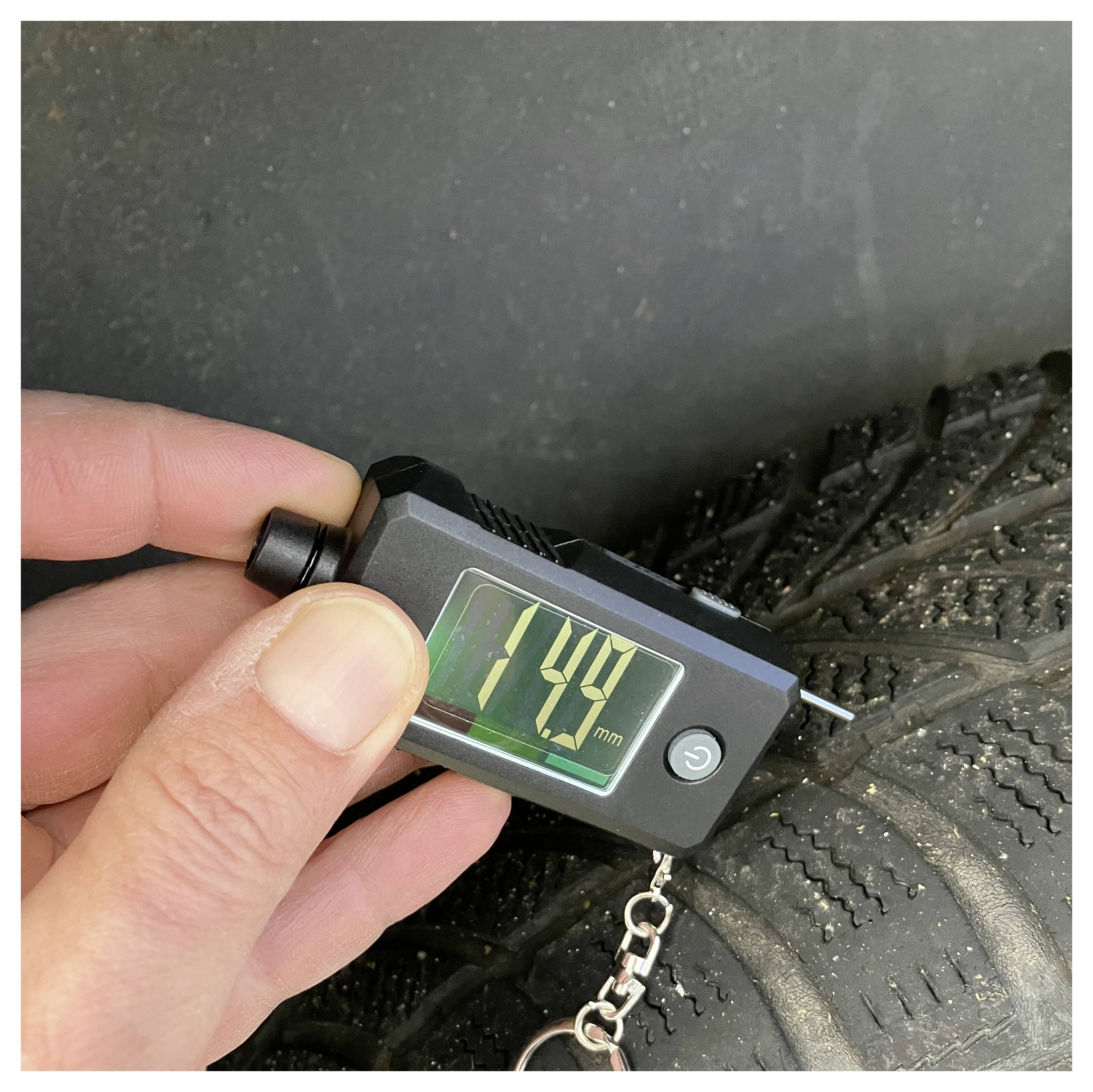 Digitální měřidlo hloubky dezénu pneumatiky měřící pneumatiku, zobrazující hodnotu 4,4 mm.