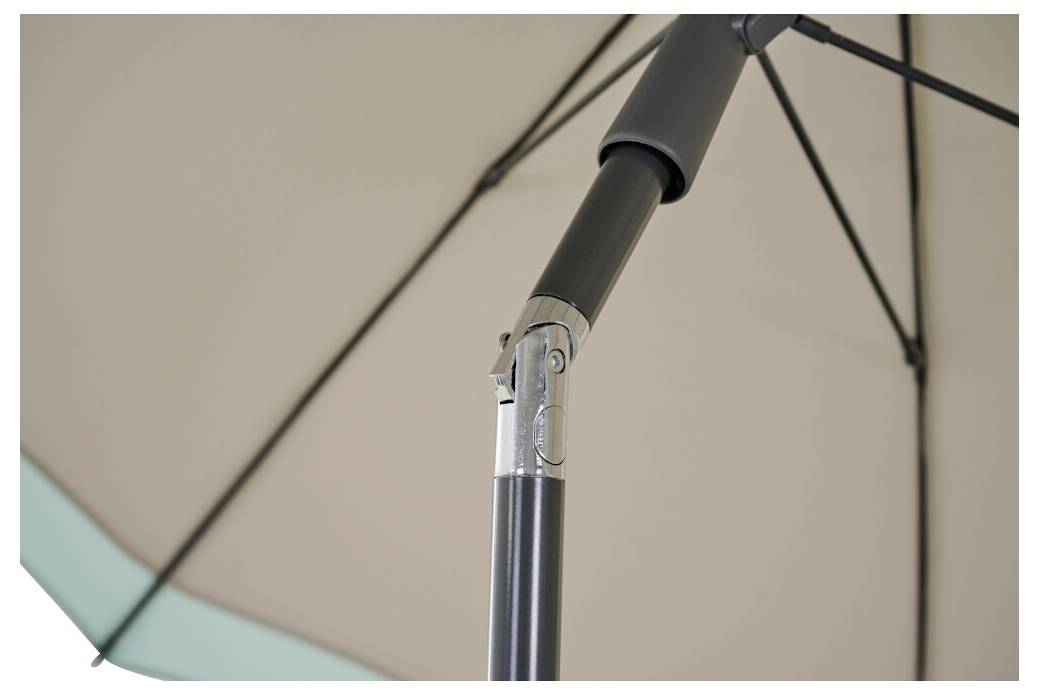 Detailní záběr na béžový sloup venkovního deštníku a spodní strana střešnice, zobrazující kovový nosný spoj a žebra.