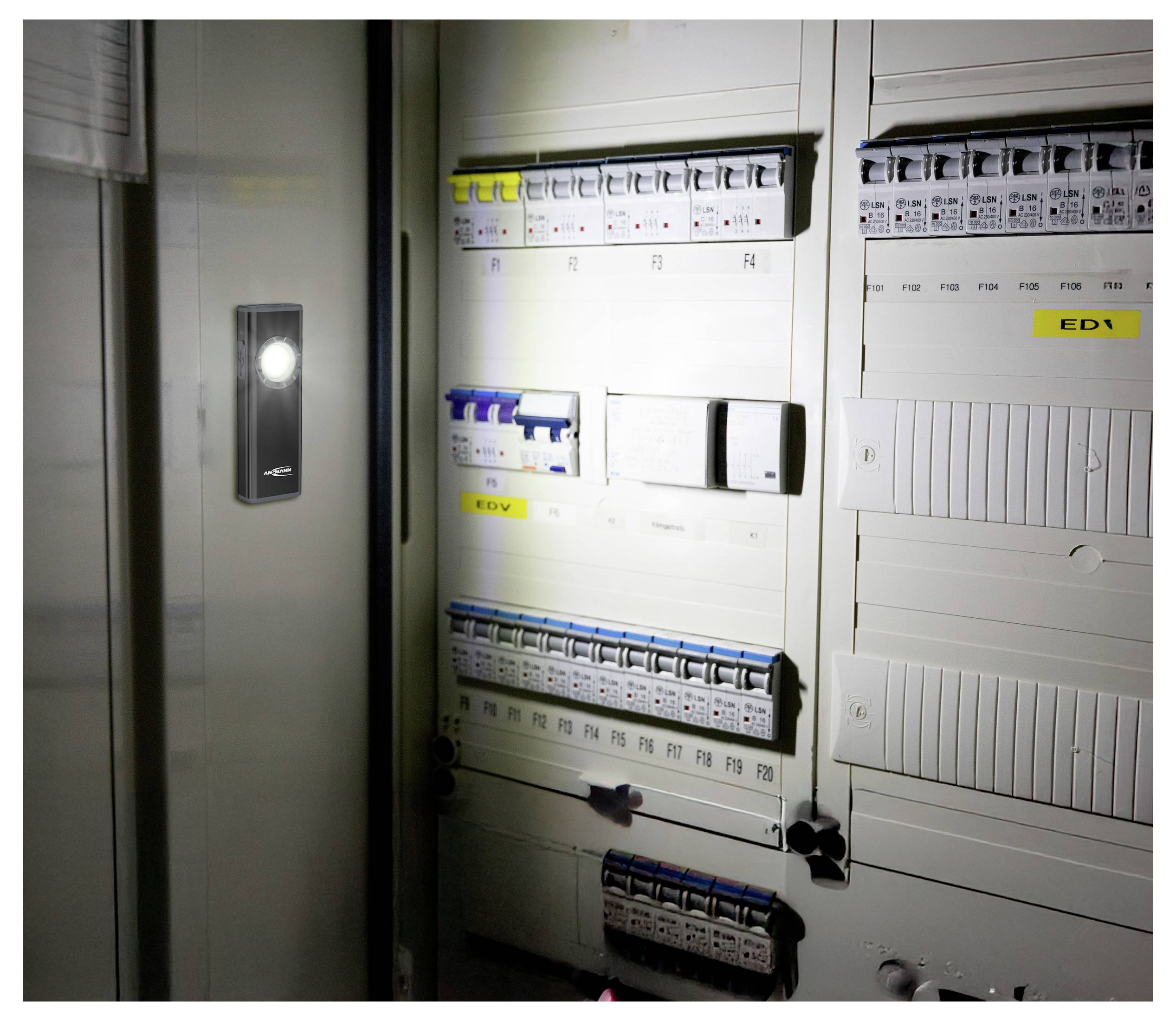 Otevřená skříň elektrického ovládání s řadami pojmenovaných jističů a svítící panelovou lampou na levých dveřích.