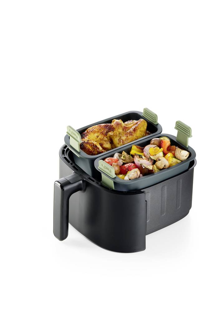 Dvousložkový fritér na vzduch se dvěma tácy: v jednom pečené kuře, v druhém směs zeleniny a brambor.
