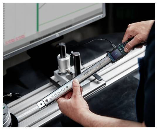 Technik měří kovovou tyč digitální posuvkou na stroji v dílně nebo výrobním prostředí.